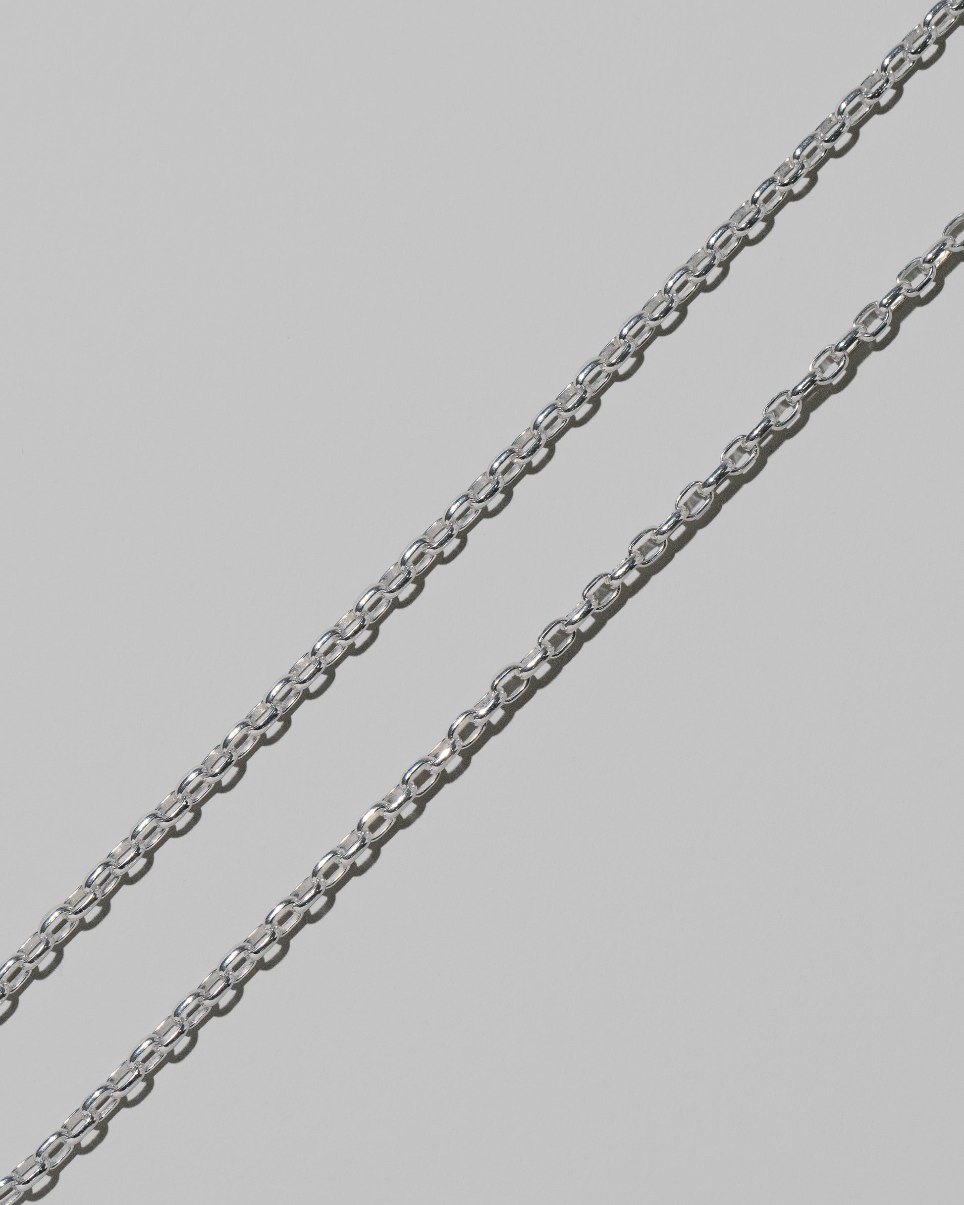 Closeup details of the CRZM 3.2mm Sterling Silver Short Loop Chain Necklace on light color background.