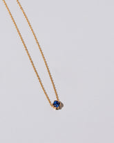 Closeup view of the Sapphire Sun & Moon Necklace on light color background.