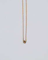 Closeup view of the Champagne Diamond Sun & Moon Necklace on light color background.