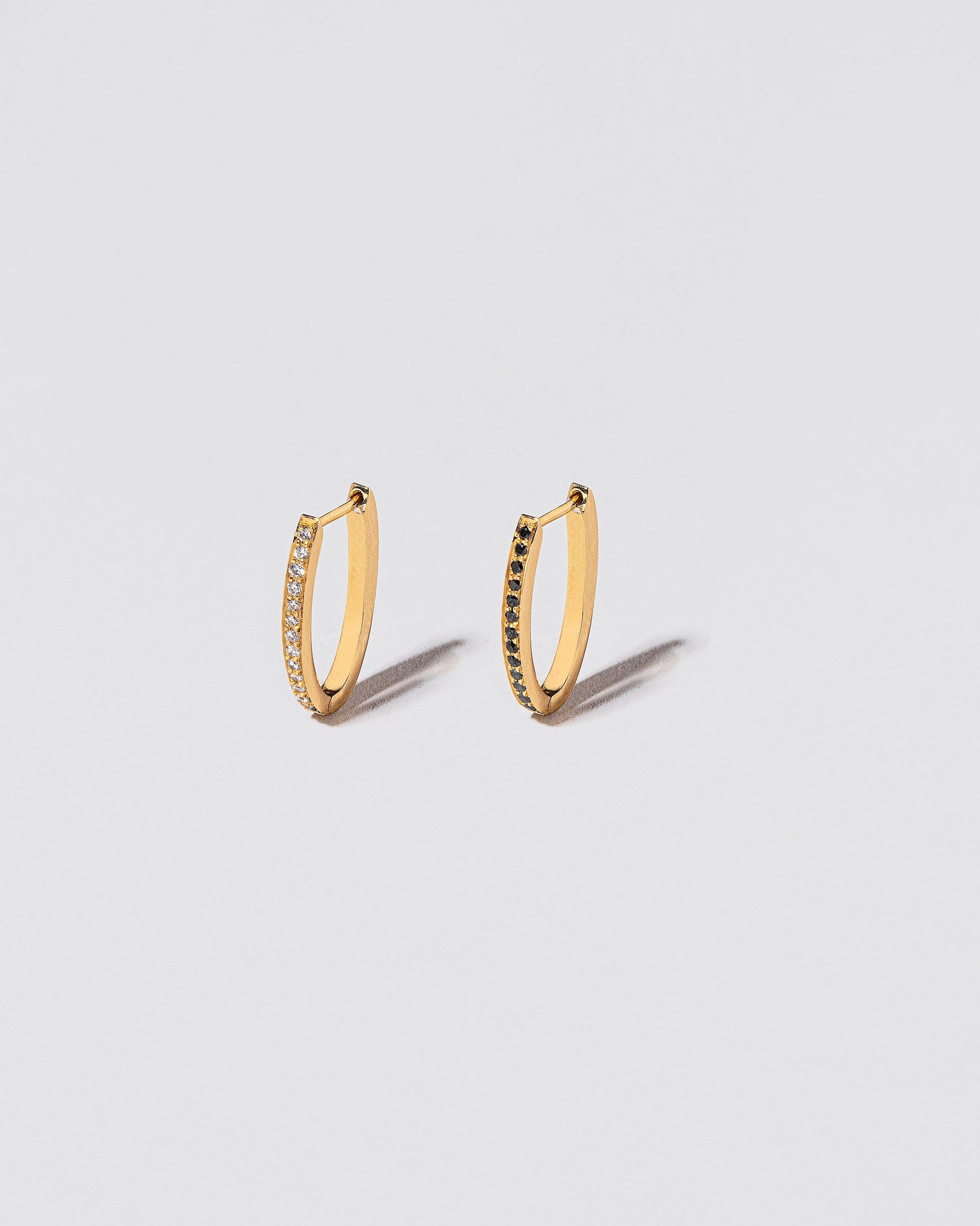 Gold Mismatch Black & White Diamond Tiny Loop Hoop Earrings on light color background.