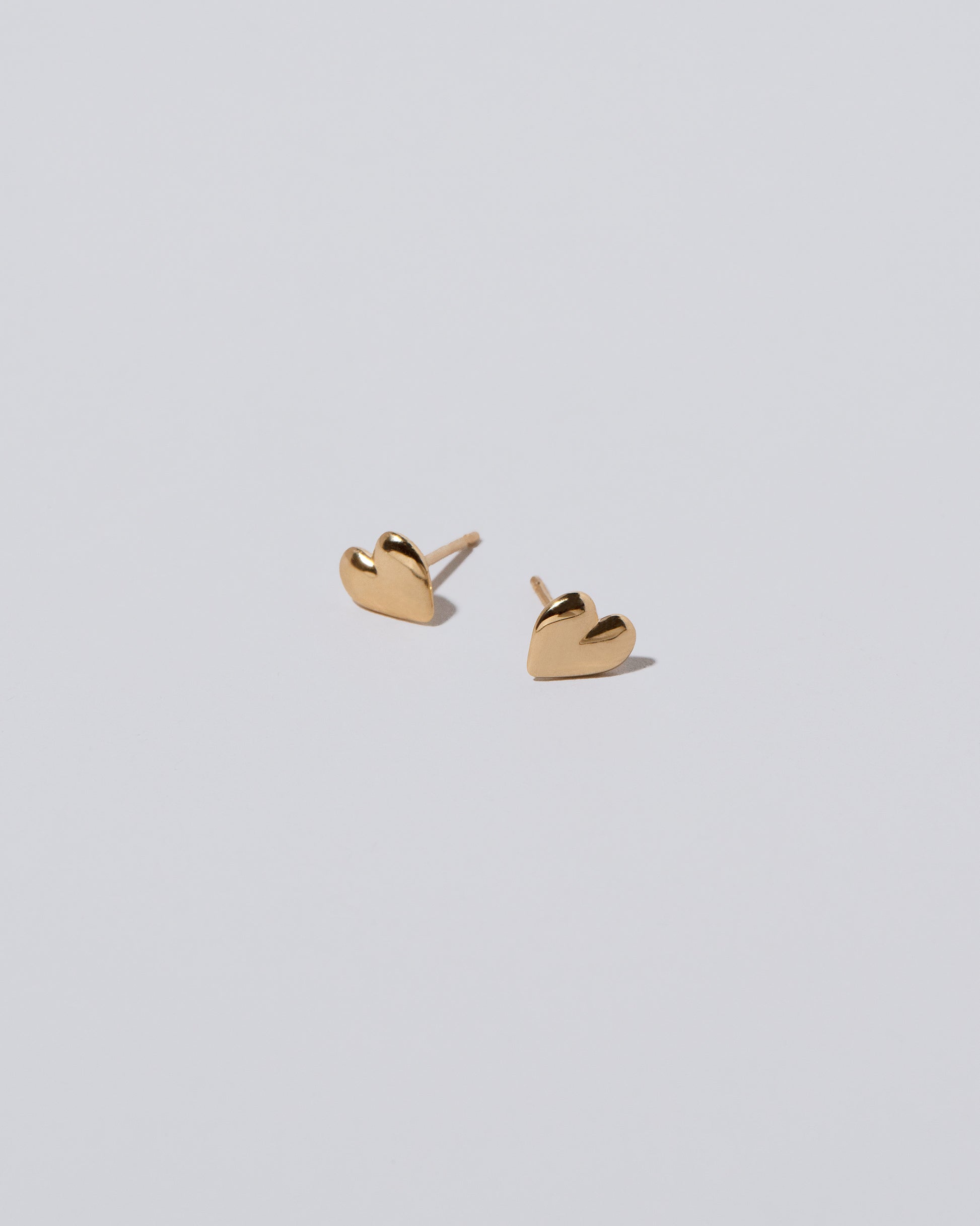 Closeup details of Shape One Small Thousand & One Night Heart Stud Earrings on light color background.