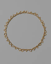 Gold Flexure Necklace on light color background.
