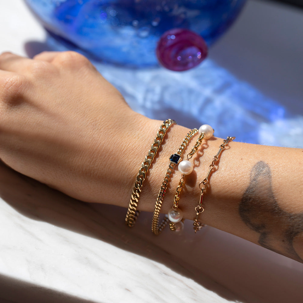product_details::2.4mm Curb Chain Bracelet, Gold Blue Sapphire Fold Bracelet, Five Pearl Pearl Station Bracelet Short Loop Chain and Vintage Bar Link Charm Chain Bracelet on model.