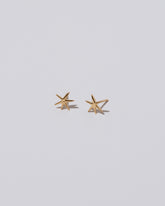 Closeup details of Shape Two Small Verve Six Point Star Stud Earrings on light color background.