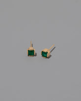 Gold Emerald Fold Earrings on light color background.