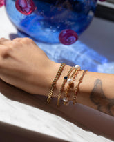 2.4mm Curb Chain Bracelet, Gold Blue Sapphire Fold Bracelet, Five Pearl Pearl Station Bracelet Short Loop Chain and Vintage Bar Link Charm Chain Bracelet on model.
