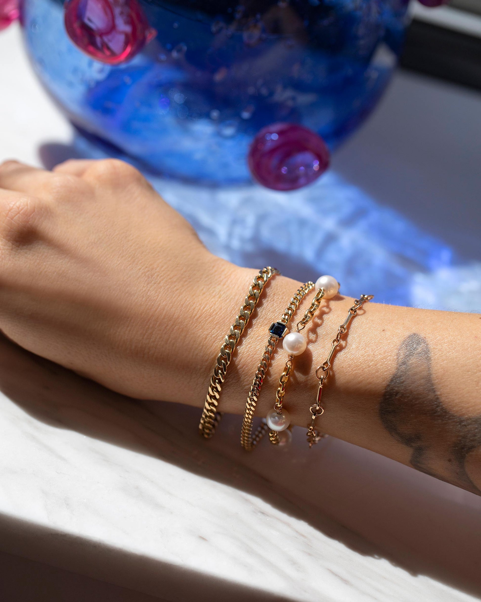 2.4mm Curb Chain Bracelet, Gold Blue Sapphire Fold Bracelet, Five Pearl Pearl Station Bracelet Short Loop Chain and Vintage Bar Link Charm Chain Bracelet on model.