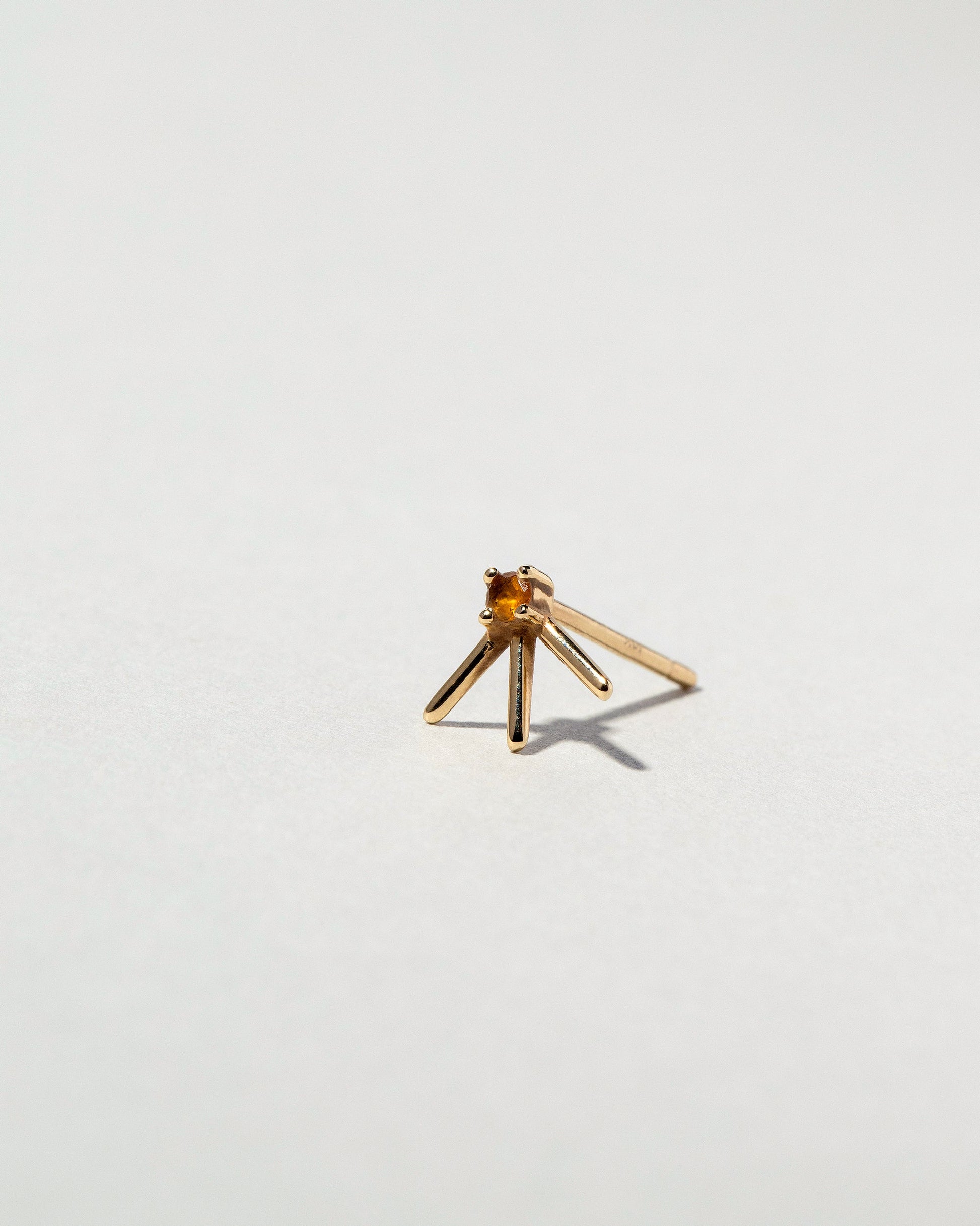 View from the side of the Gold Citrine Sun Ray Stud Earring Single on light color background.