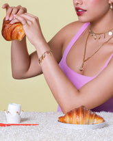 Styled image featuring the Twisted Chain Bracelet, Short Loop Chain Necklace, styled with the Wild Strawberry Charm, Bruised Banana Charm, Waffle Charm, Orange Slice Charm, Bacon Charm, Nine Sunny Side Up Egg Charm, Ruby Pavé Strawberry Charm, Long Loop Chain Necklace, Flapjack Pancake Charm and Melon Slice Charms on model.