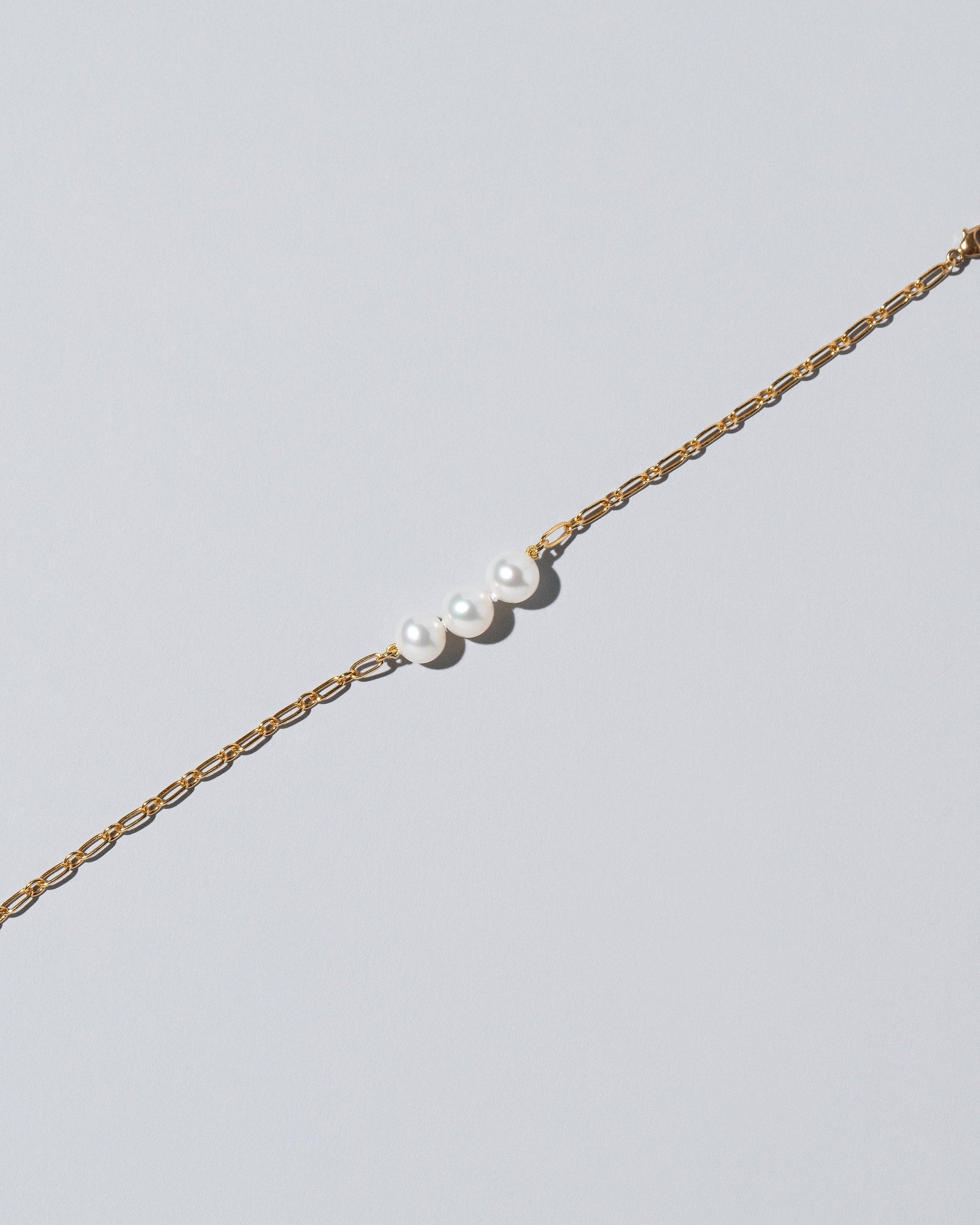Closeup details of the Three Pearl Station Bracelet Hot Dog Chain on light color background.