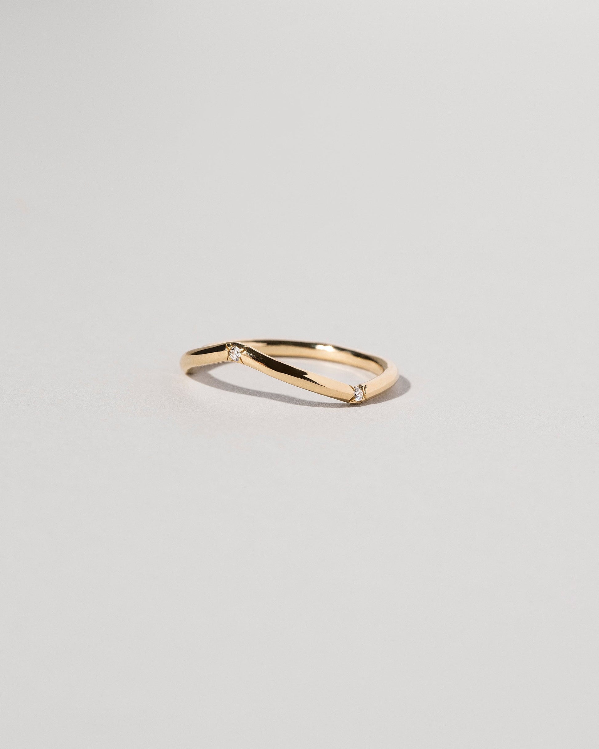 View from the side of the Gold Three Stone White Diamond Low Peak Band on light color background.
