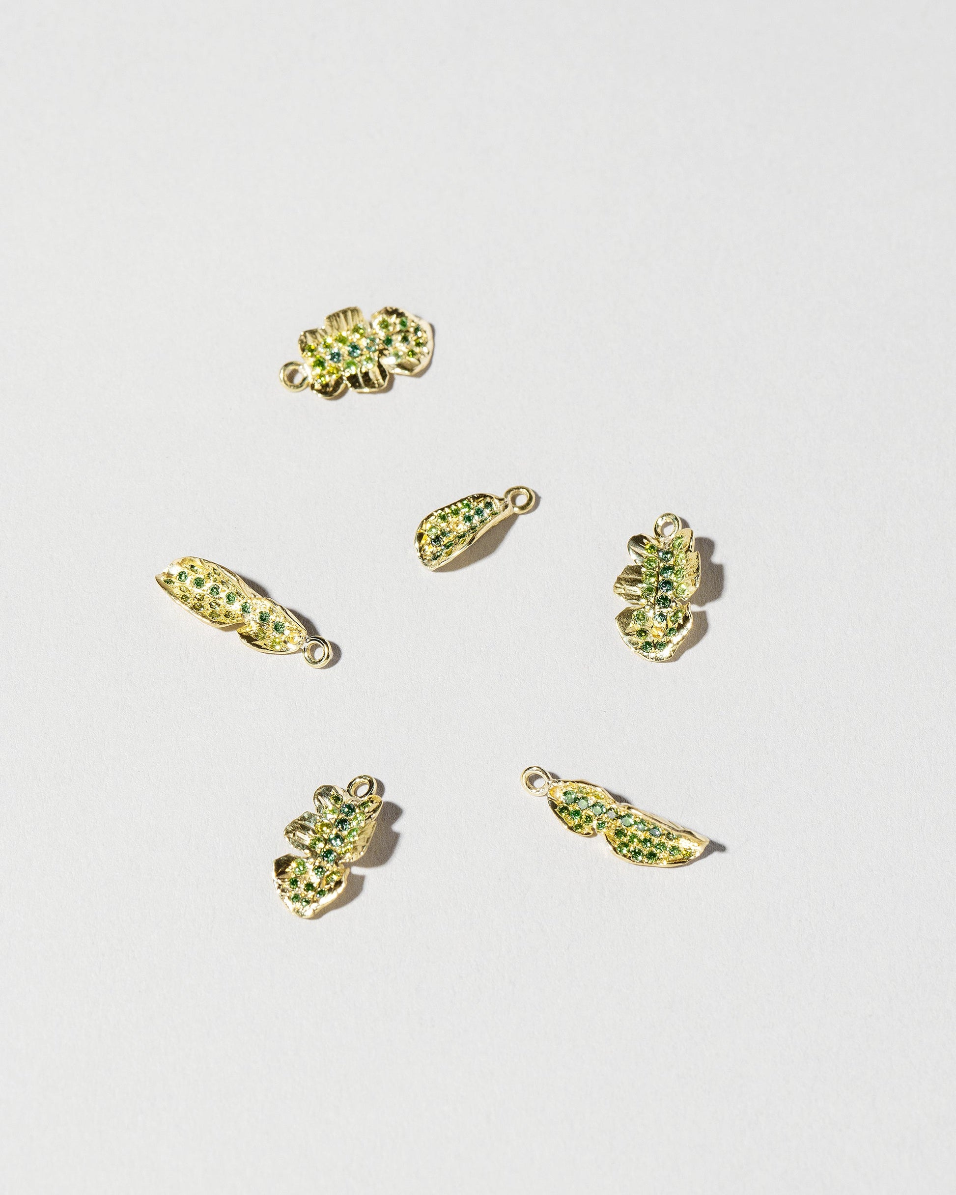 Group of Arugula Charms on light color background.