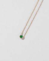 Closeup details of the Emerald Sun & Moon Necklace on light color background.