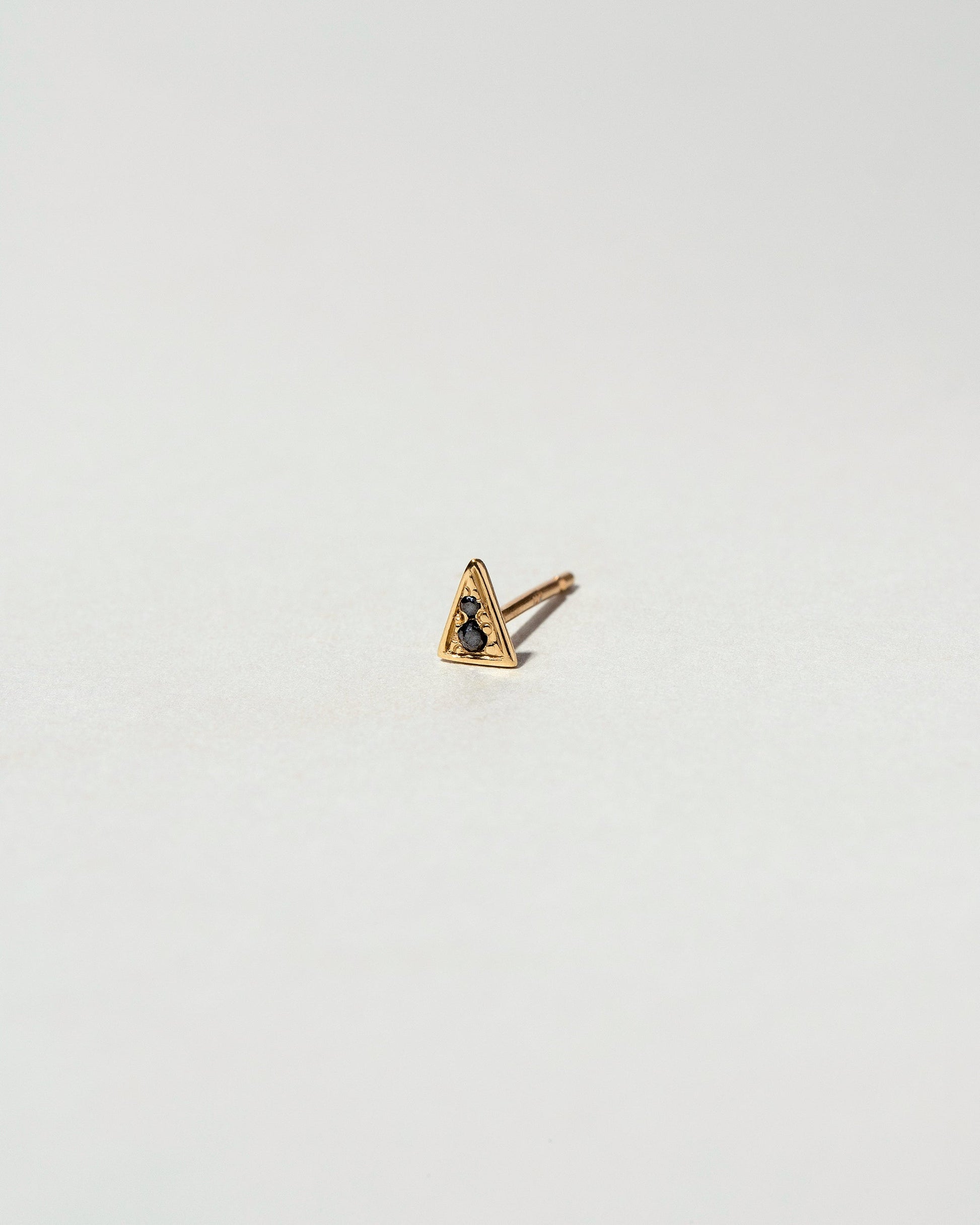 Gold Black Diamond Triangle Stud Earring Single on light color background.