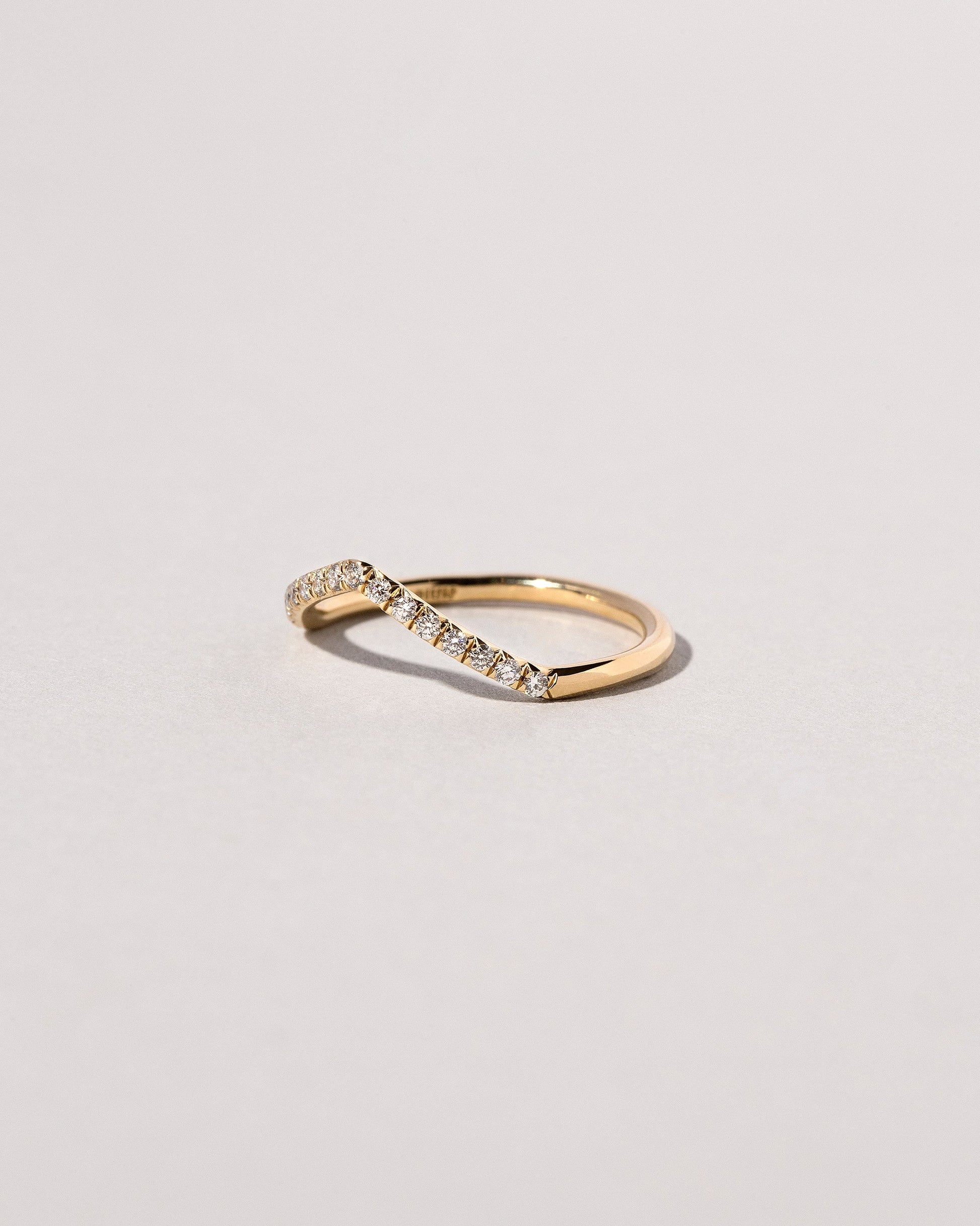 View from the side of the Gold Pavé White Diamond Low Peak Band on light color background.