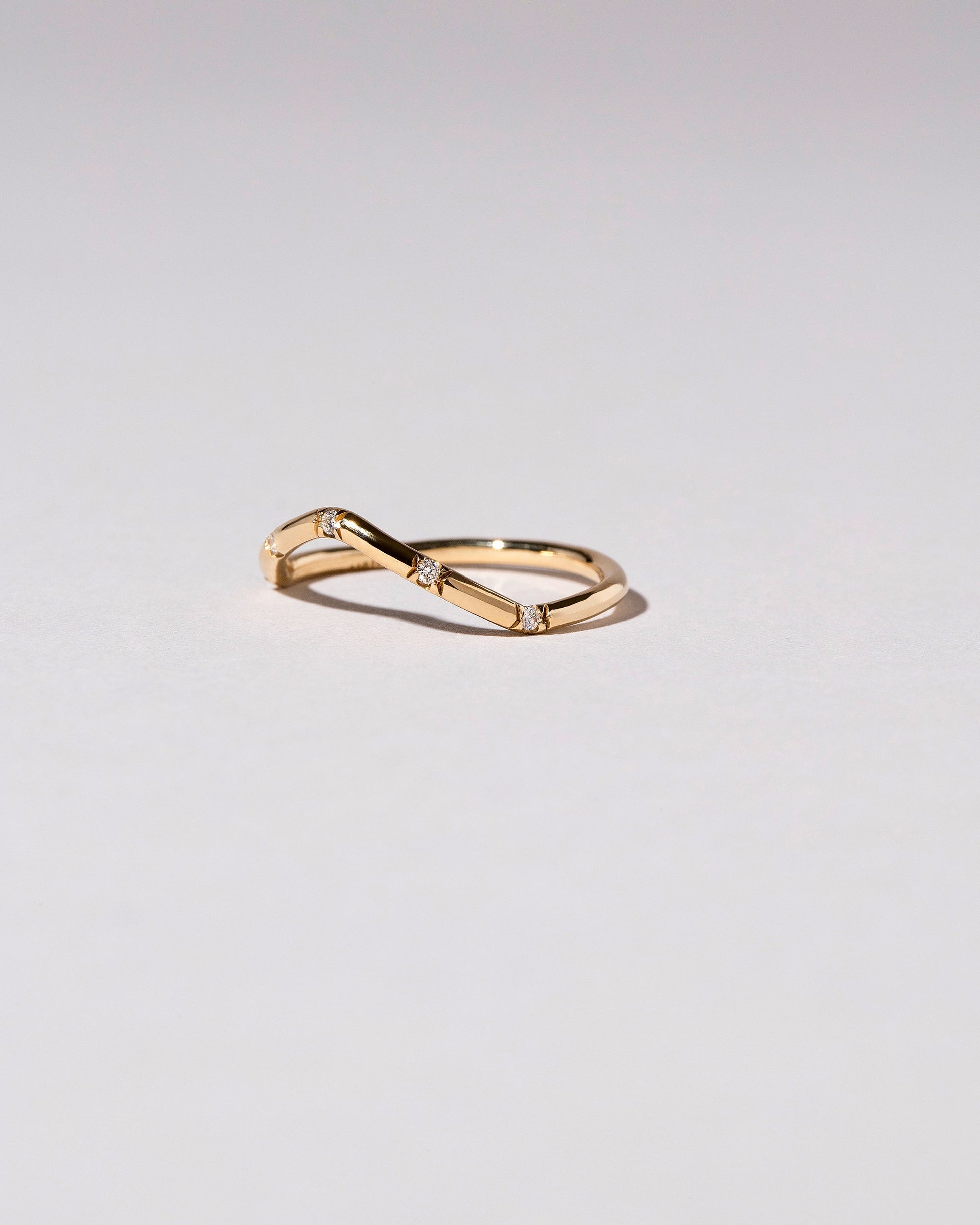 View from the side of the Gold White Diamond Five Stone Low Peak Band on light color background.