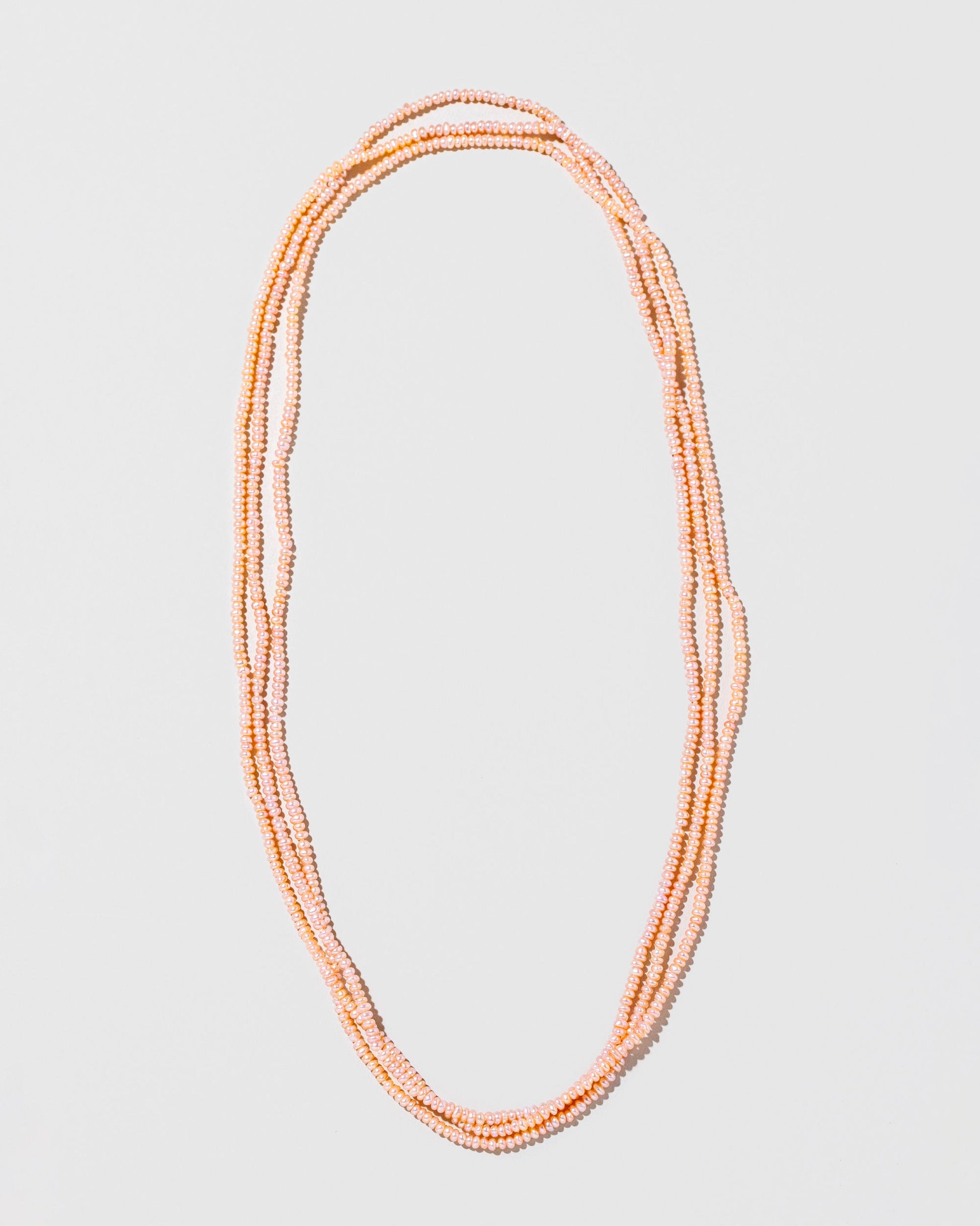 Pink Peony Seed Pearl Rope Necklace on light color background.