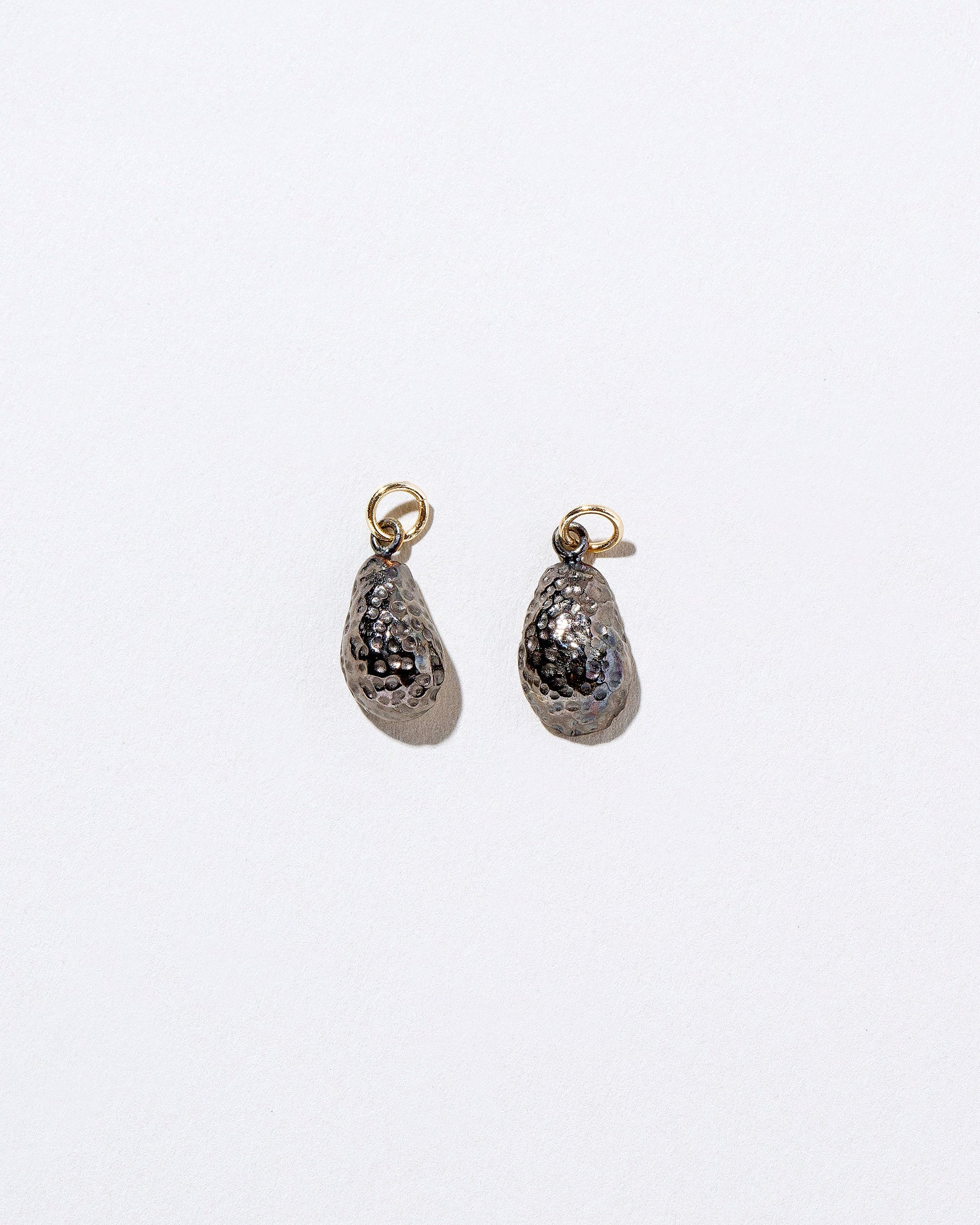 View from the back of the Halved Avocado Charms on light color background.
