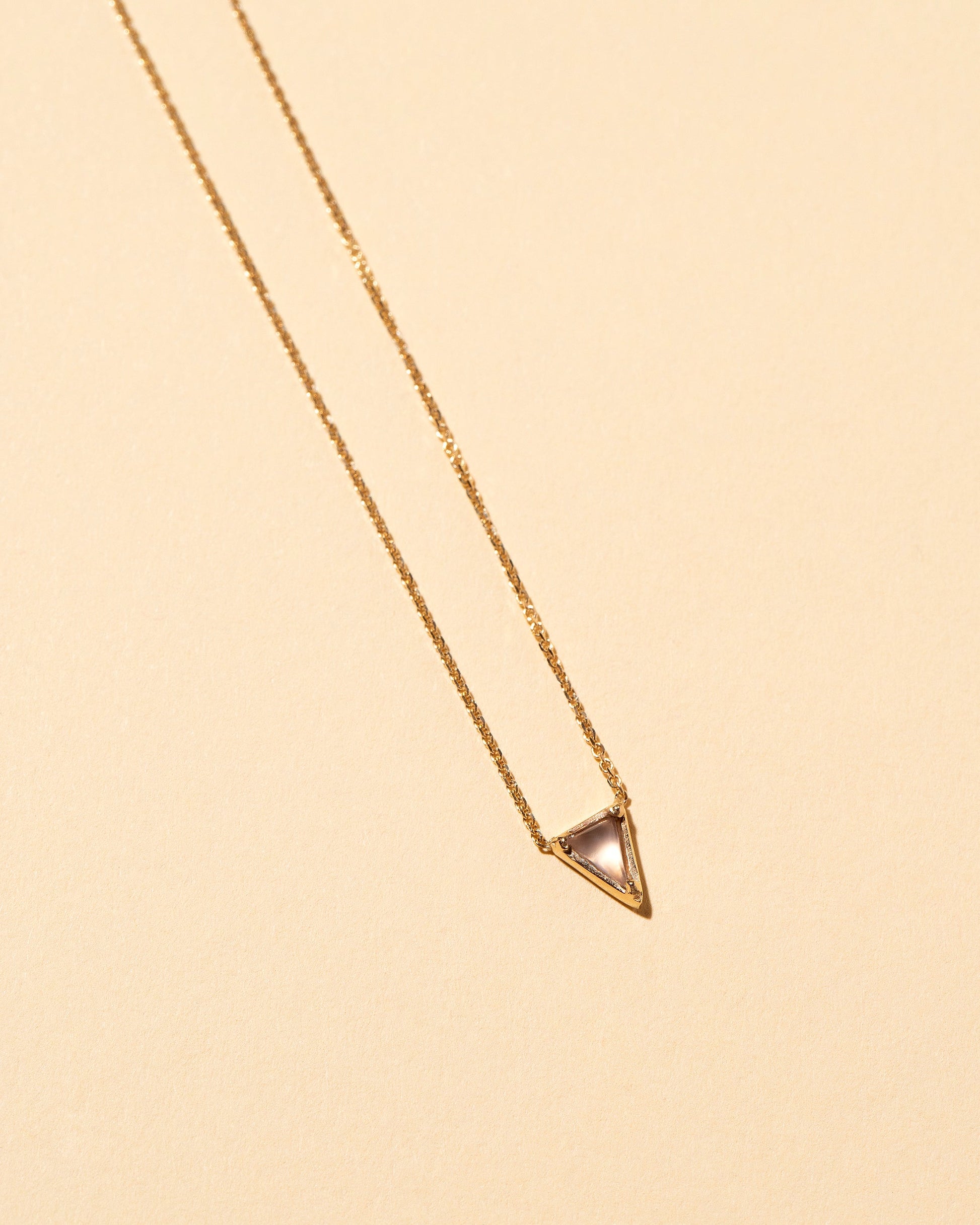 Closeup details of the Gold Blue Chalcedony Triangle Necklace on light color background.