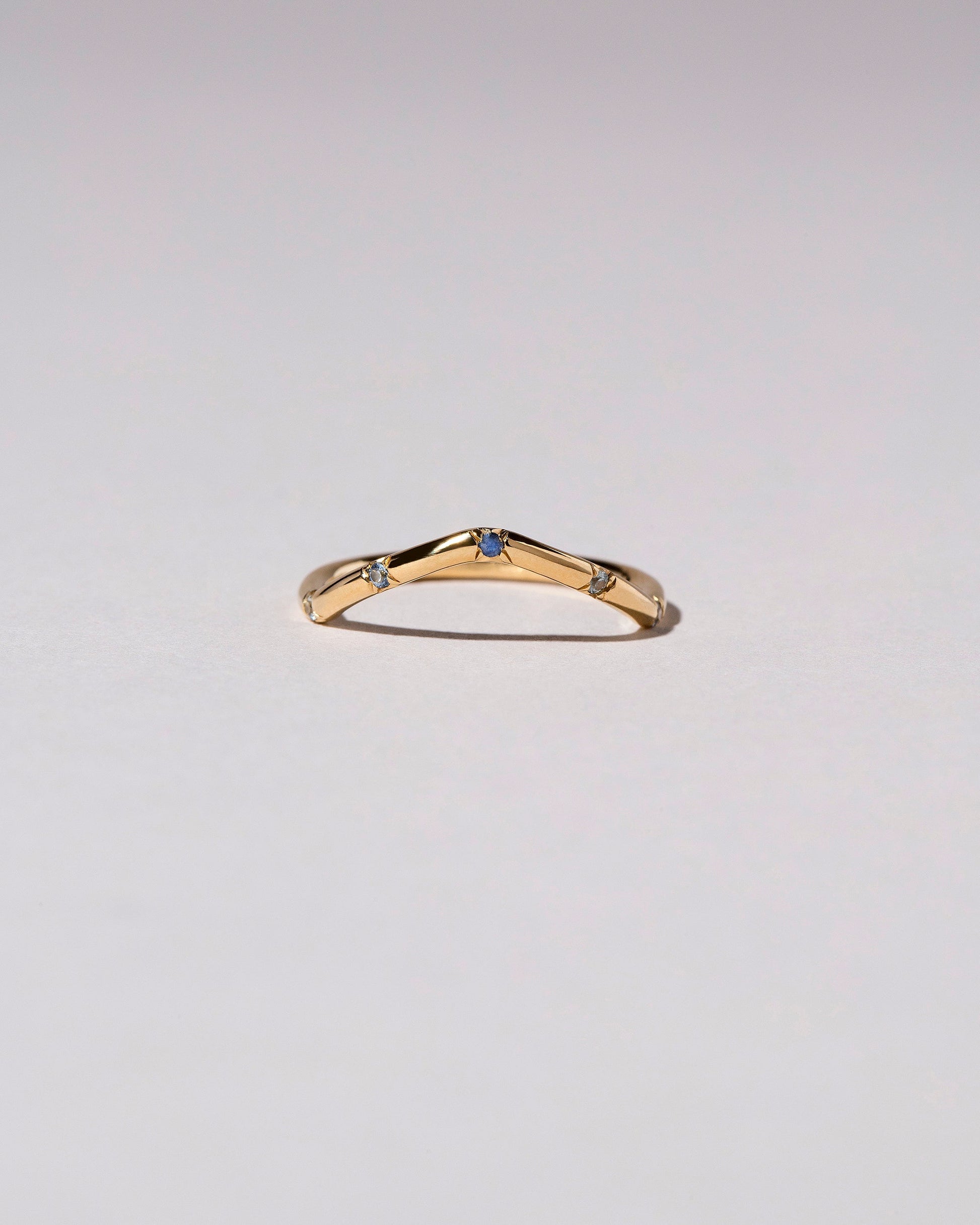 Gold Blue Sapphire Five Stone Low Peak Band on light color background.