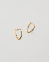 Closeup details of the Gold Solid Tiny Loop Hoop Earrings on light color background.