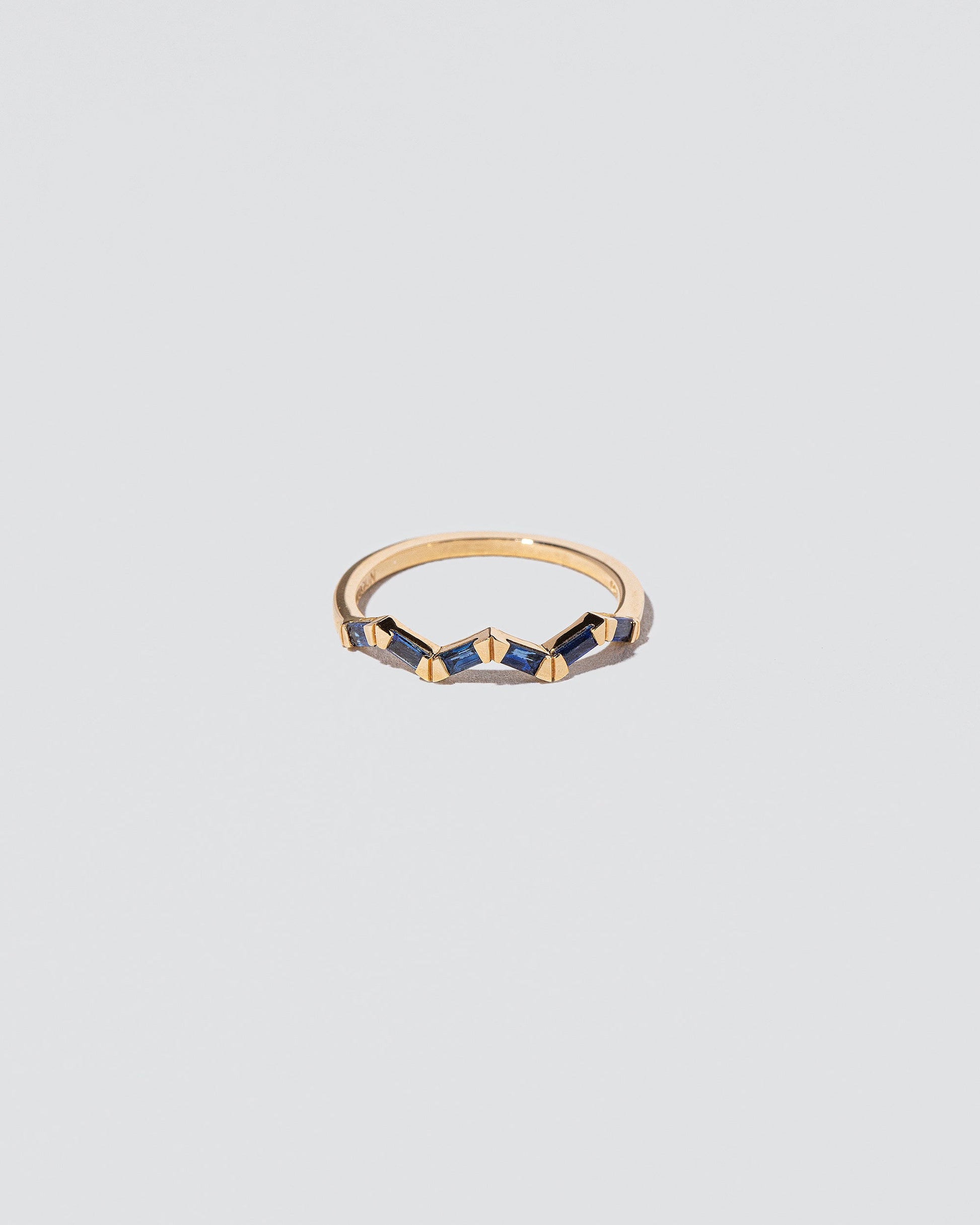 Sapphire Baguette Yellow Gold Zig Zag Band on light color background.