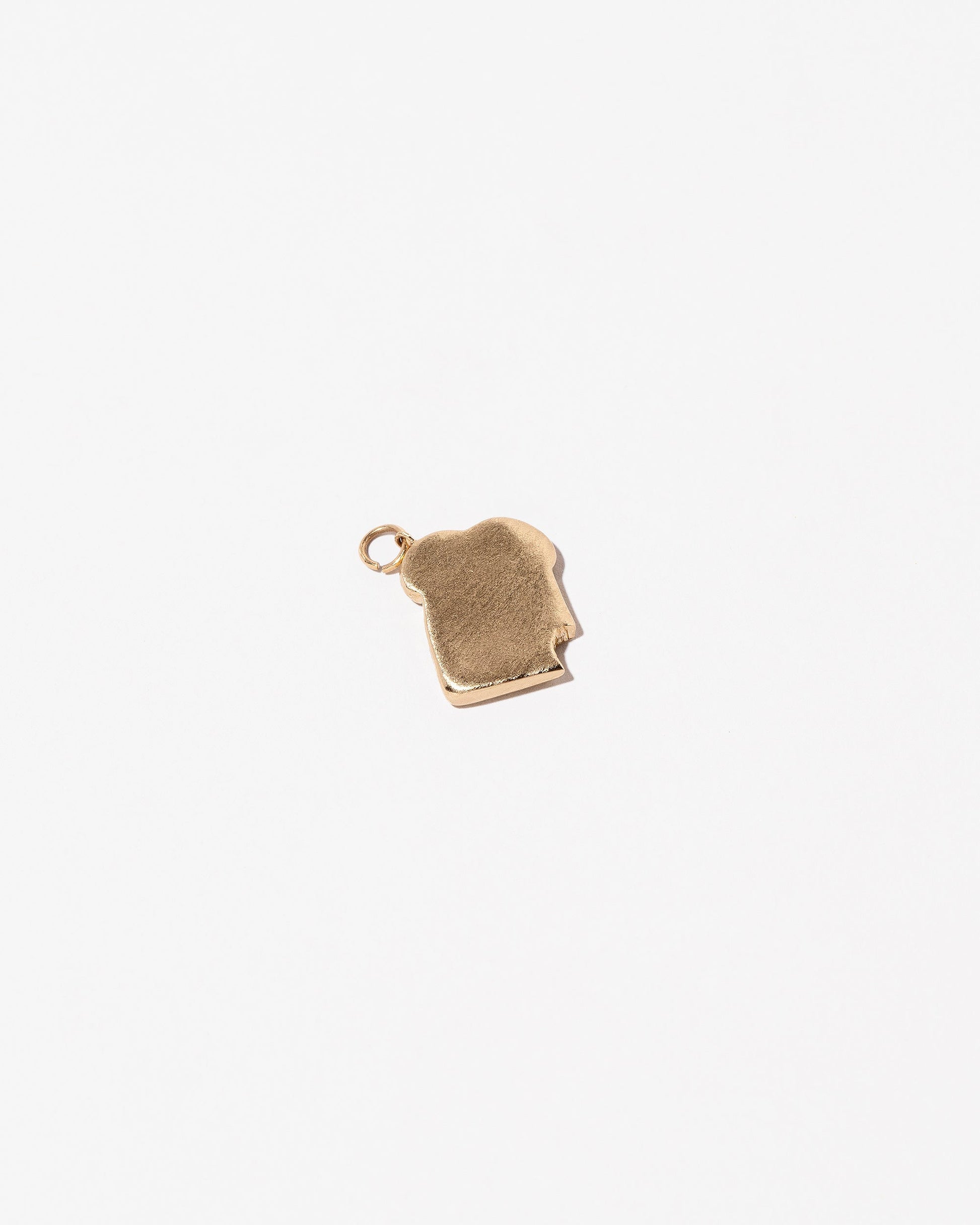 Closeup details of the Bitten Toast Charm on light color background.