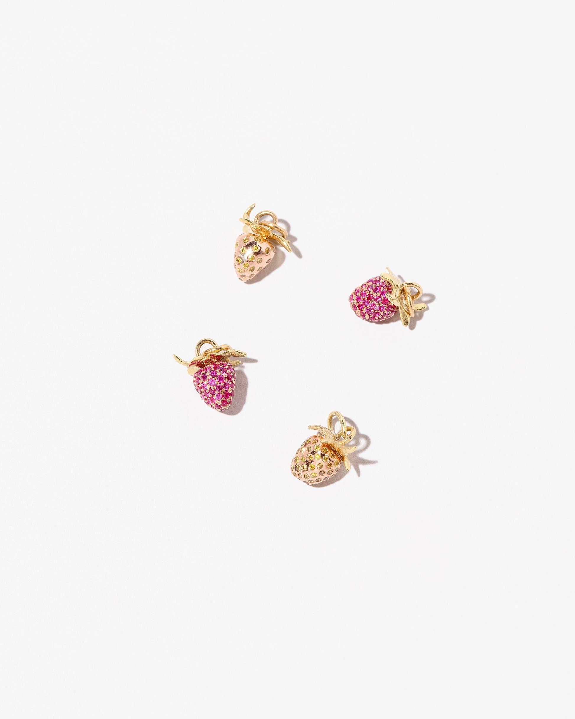 Wild Strawberry Charm, Diamond & Ruby Pavé Strawberry Charm and Ruby Pavé Strawberry Charm on light color background.