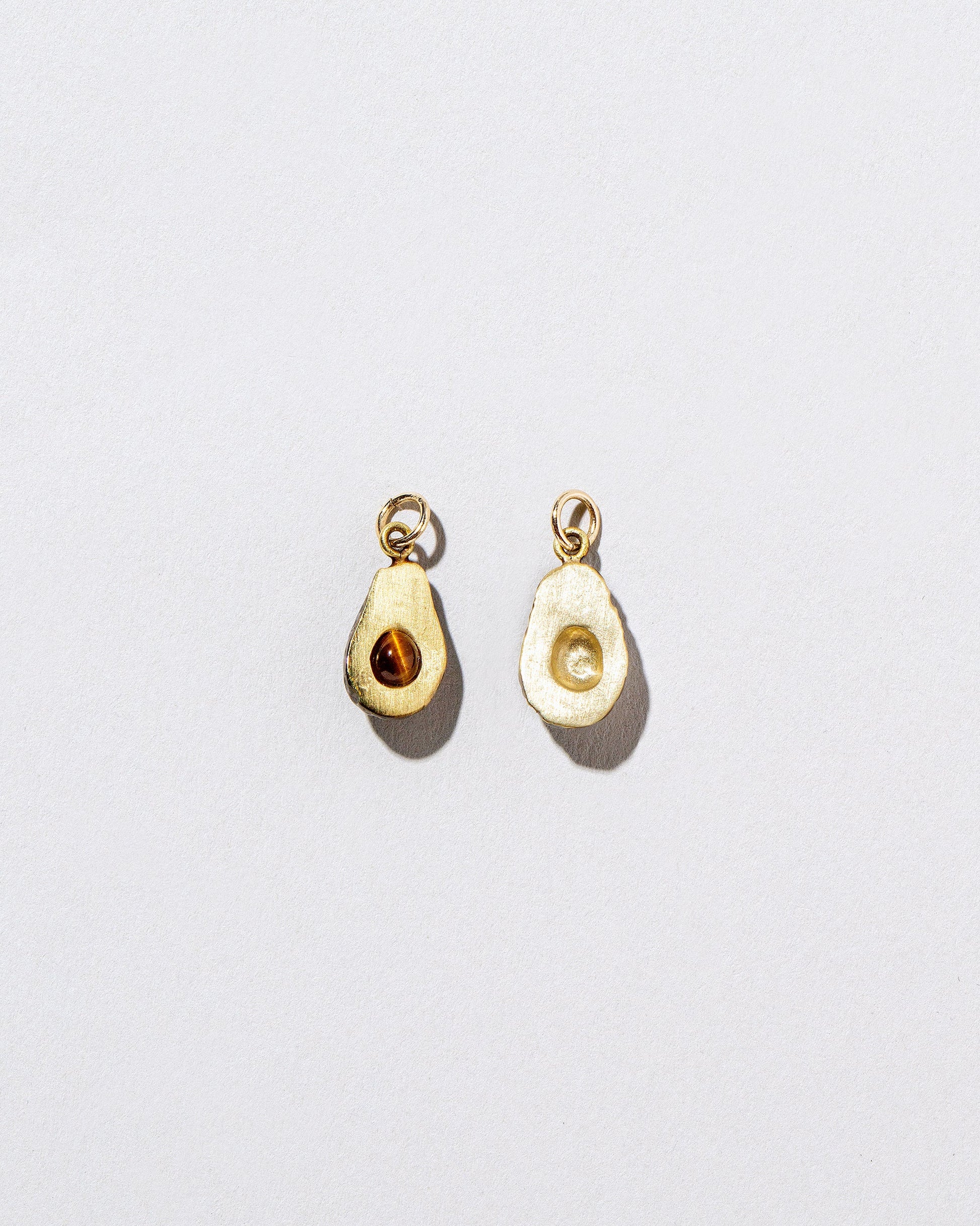 Halved Avocado Charms on light color background.