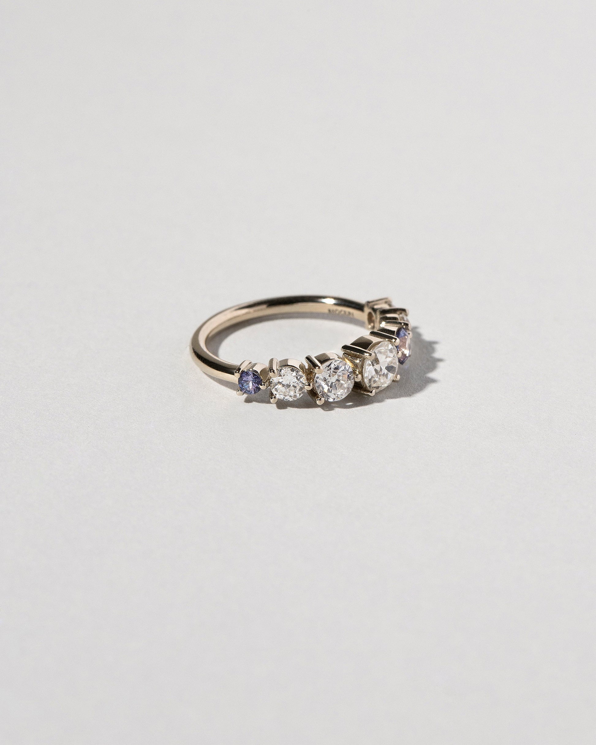 View from the side of the Diamond & Sapphire Line Cluster Ring on light color background.