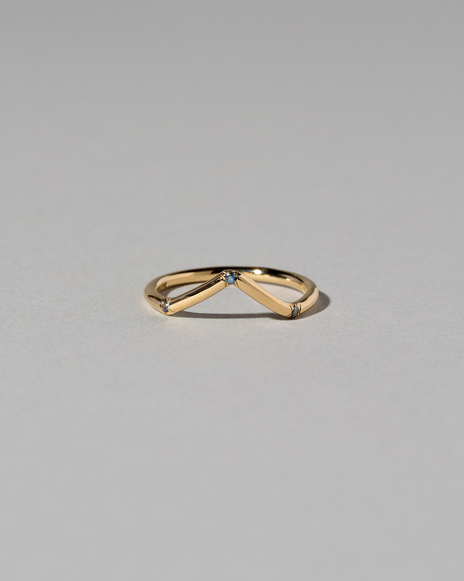 Gold Three Stone Blue Sapphire High Peak Band on light color background.