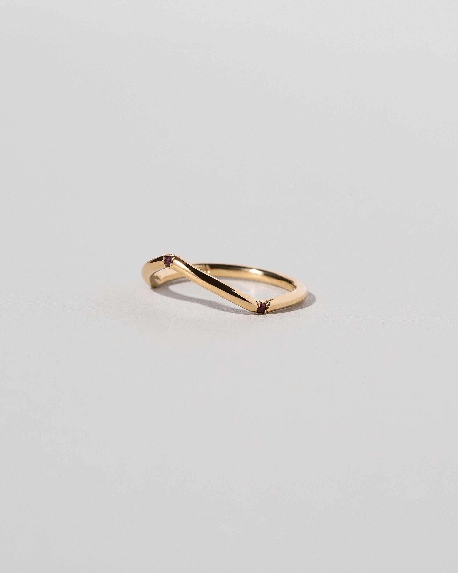 View from the side of the Gold Three Stone Garnet Low Peak Band on light color background.