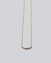 Cognac Diamond Crescent Necklace on light color background.