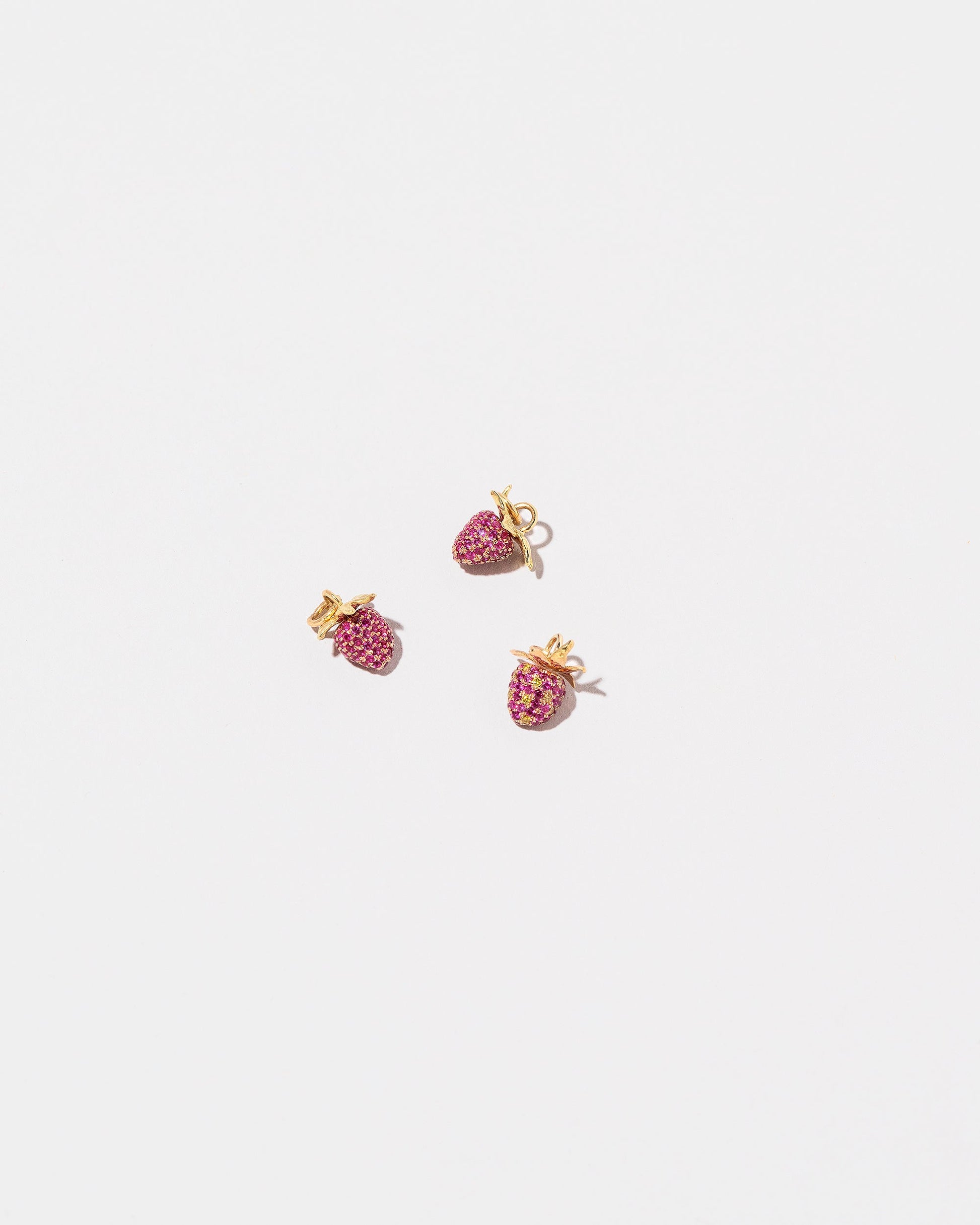 Diamond & Ruby Pavé Strawberry Charm and Ruby Pavé Strawberry Charms on light color background.