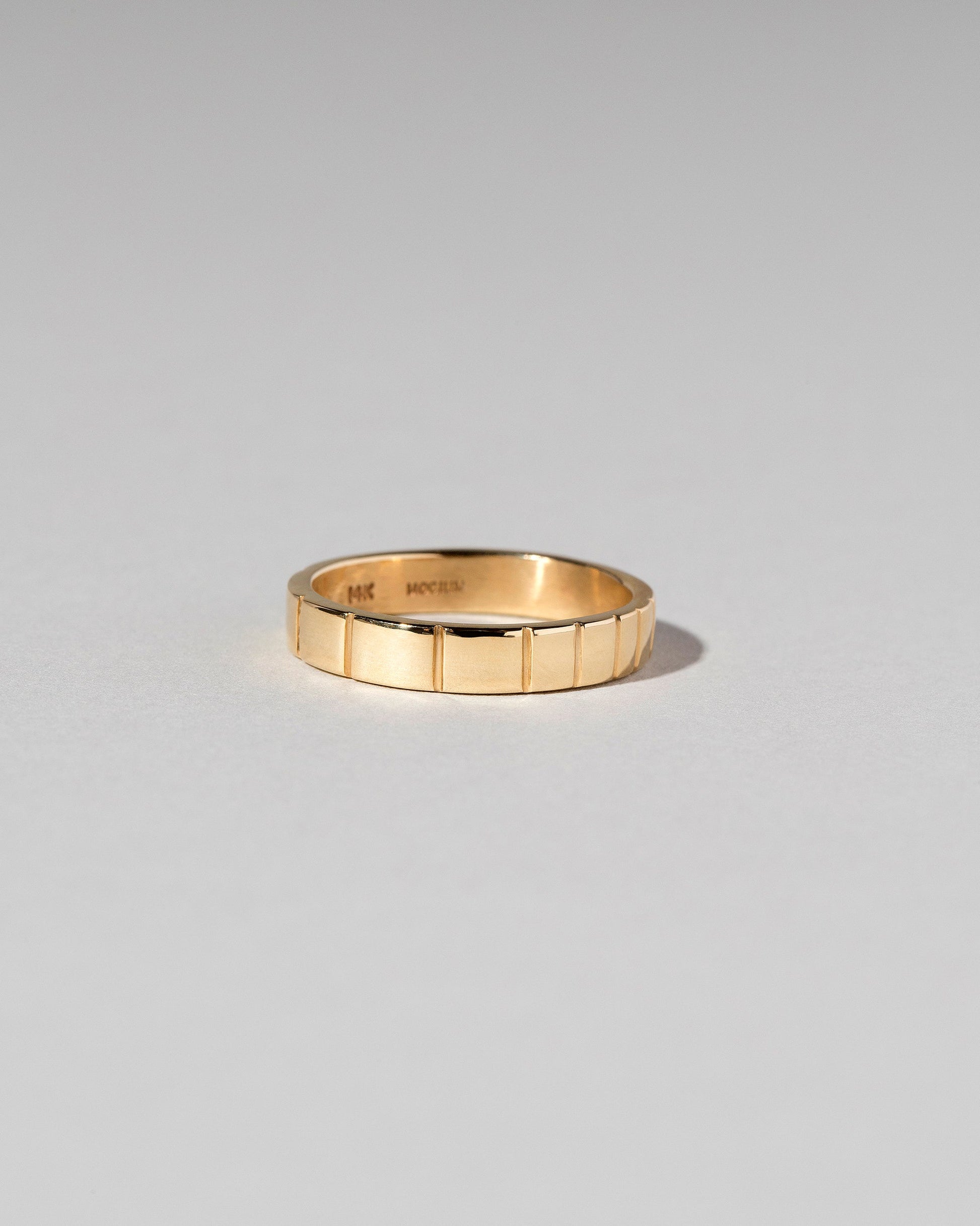 View from the side of the Gold 3mm Etched Lines Band on light color background.