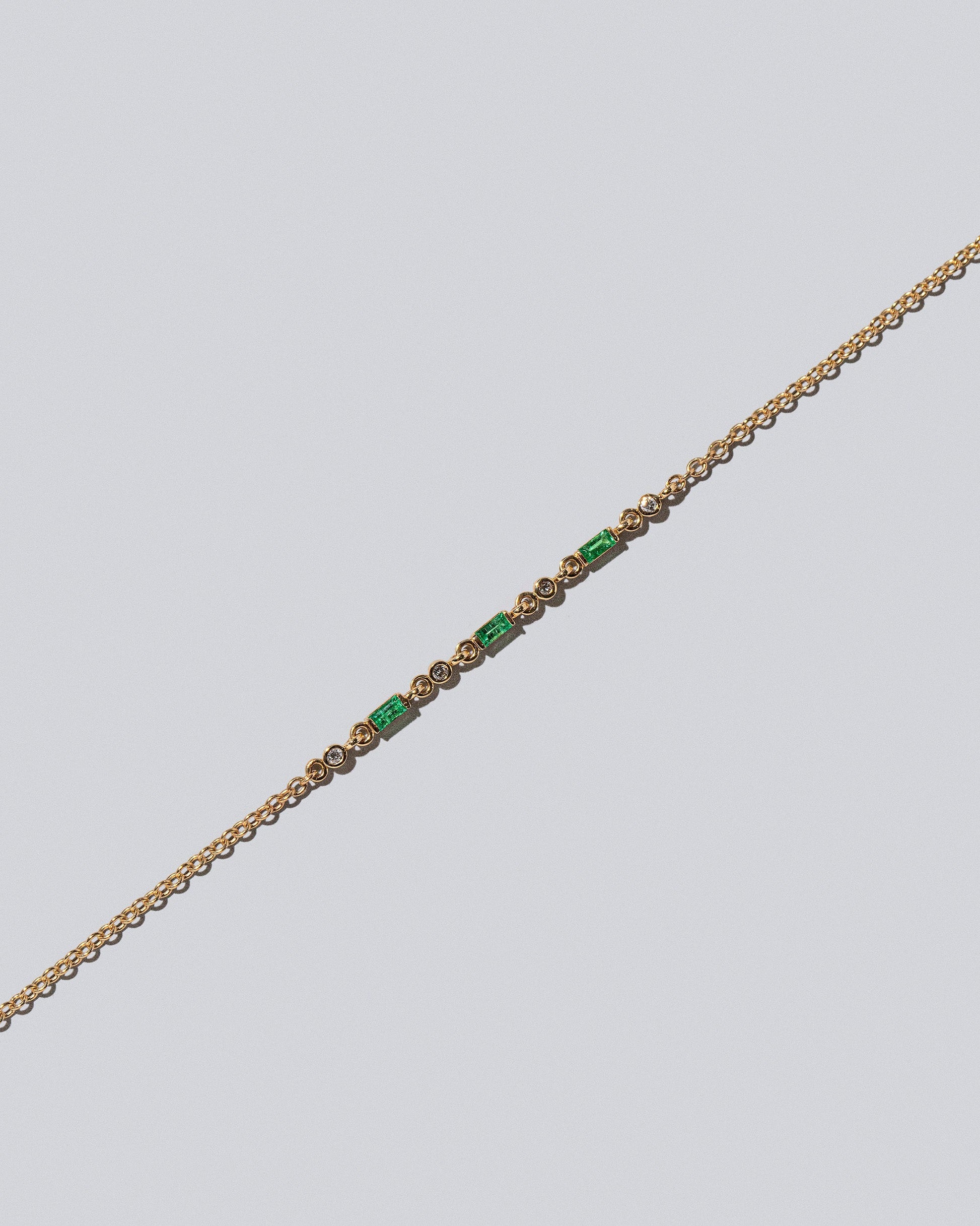 Closeup detail of the Emerald Consecutive Building Block Bracelet on light color background.