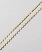 Closeup details of the Petite Pinched Loop Chain Necklace on light color background.
