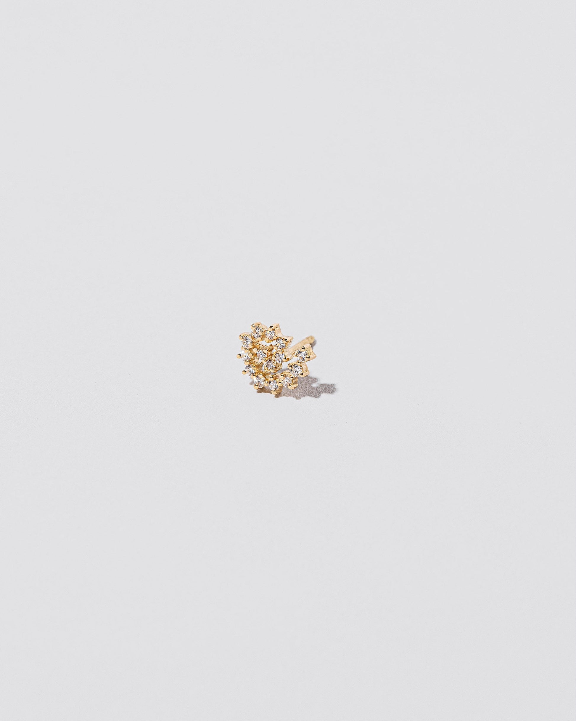 Mini White Diamond Left Spiral Stud Earring Single on light color background.