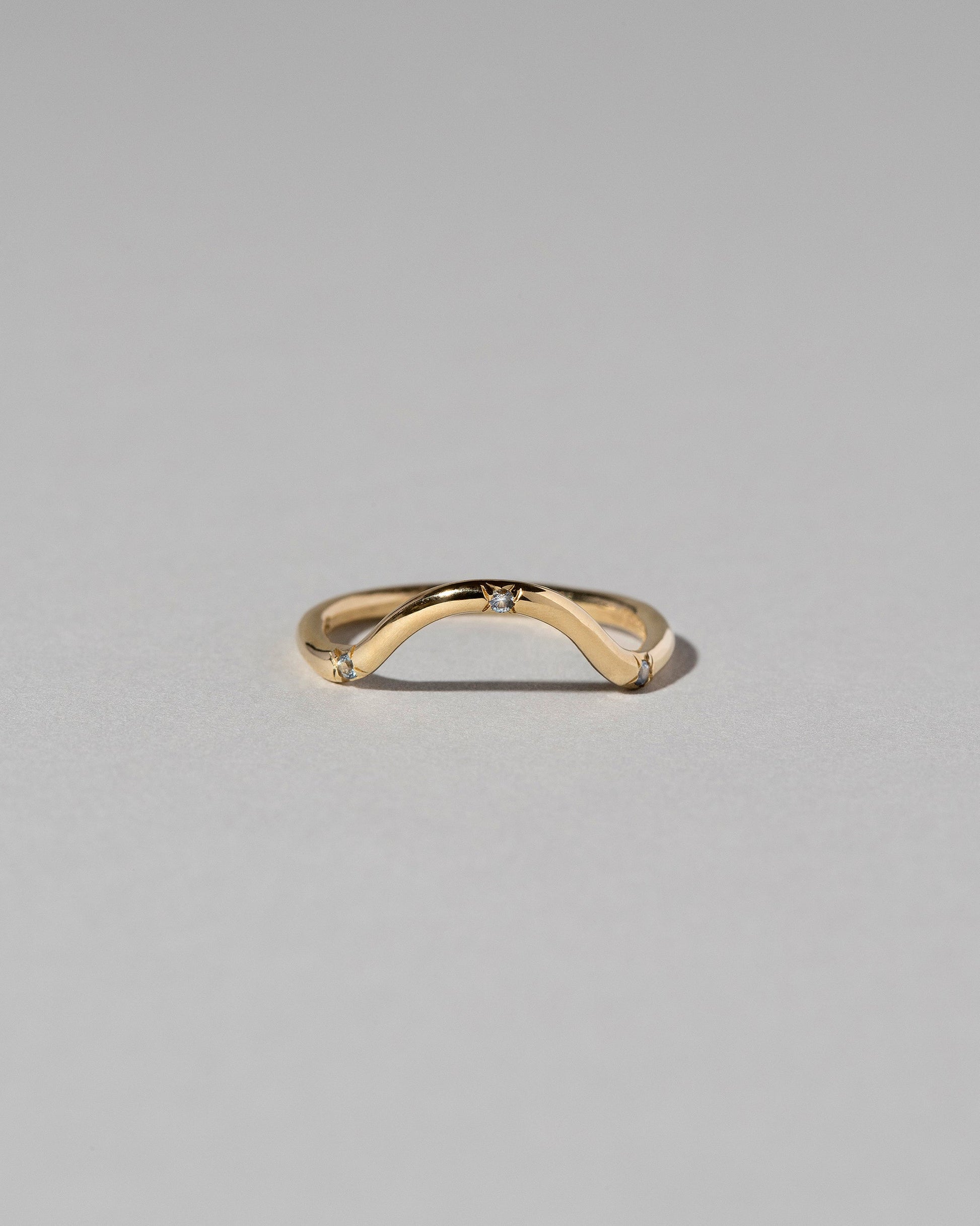 Gold Three Stone Blue Sapphire Curve Band on light color background.
