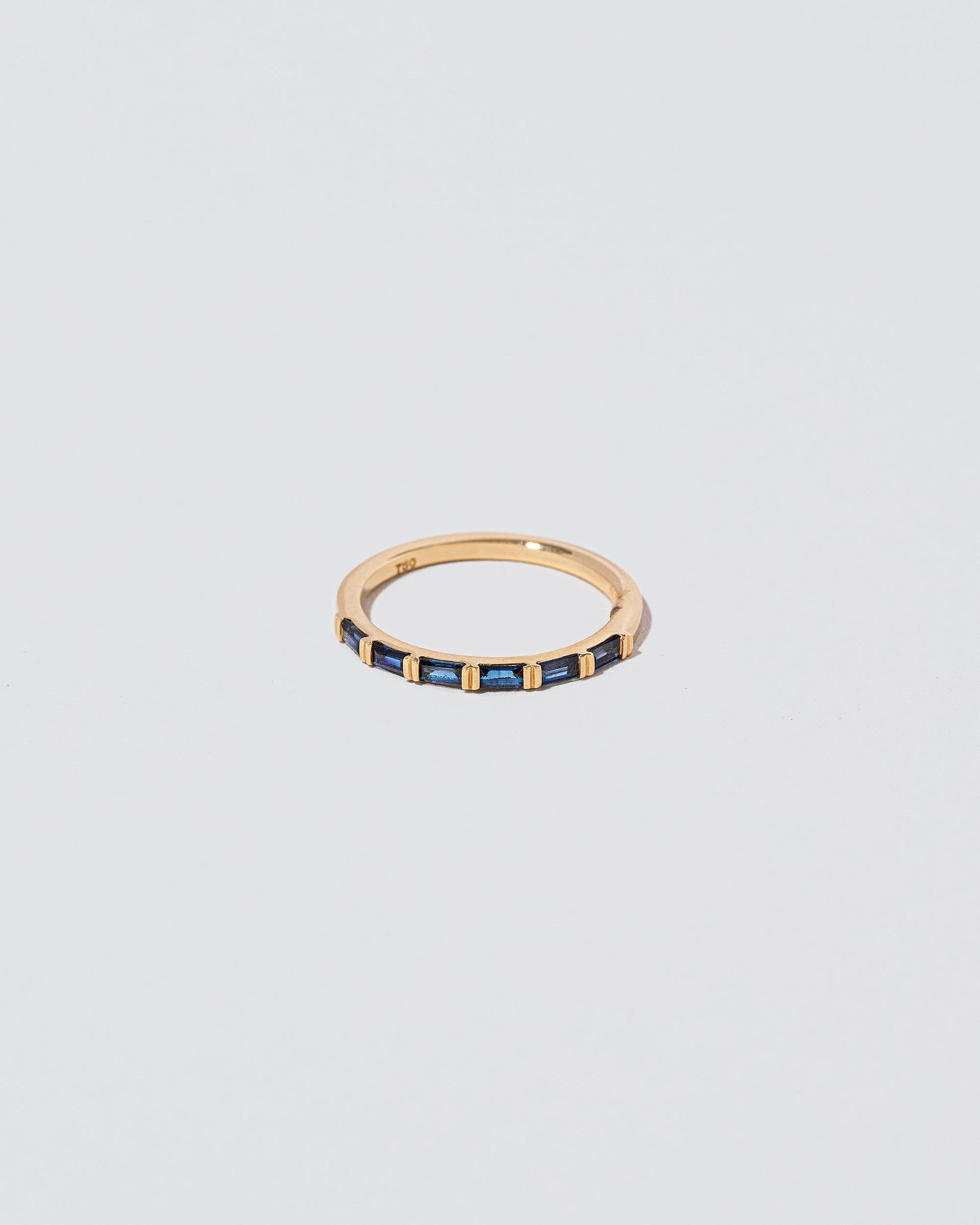 Gold Blue Sapphire Bar Baguette Band on light color background.