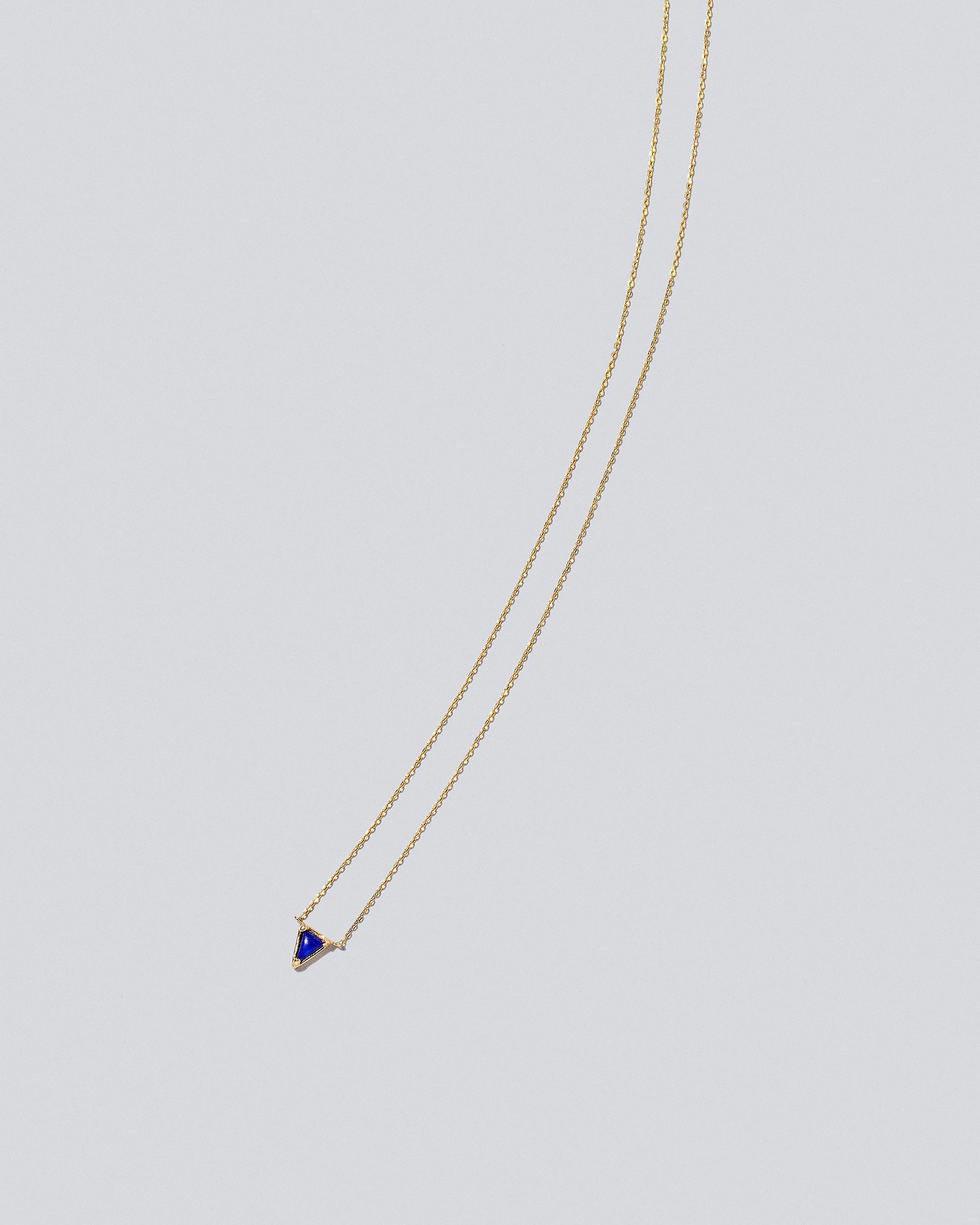 Gold Lapis Triangle Necklace on light color background.