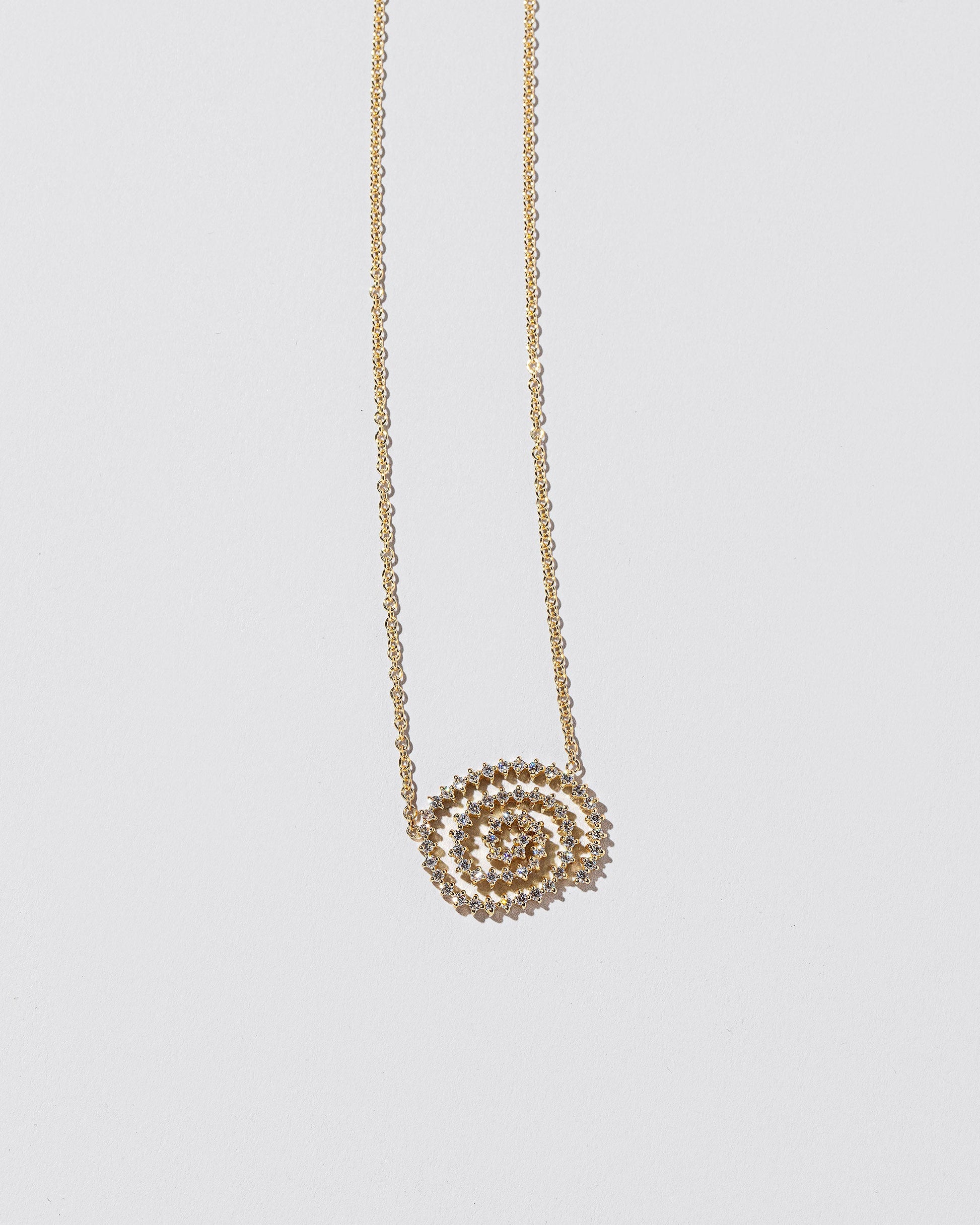 Closeup details of the White Diamond Cycle of Rebirth Necklace on light color background.