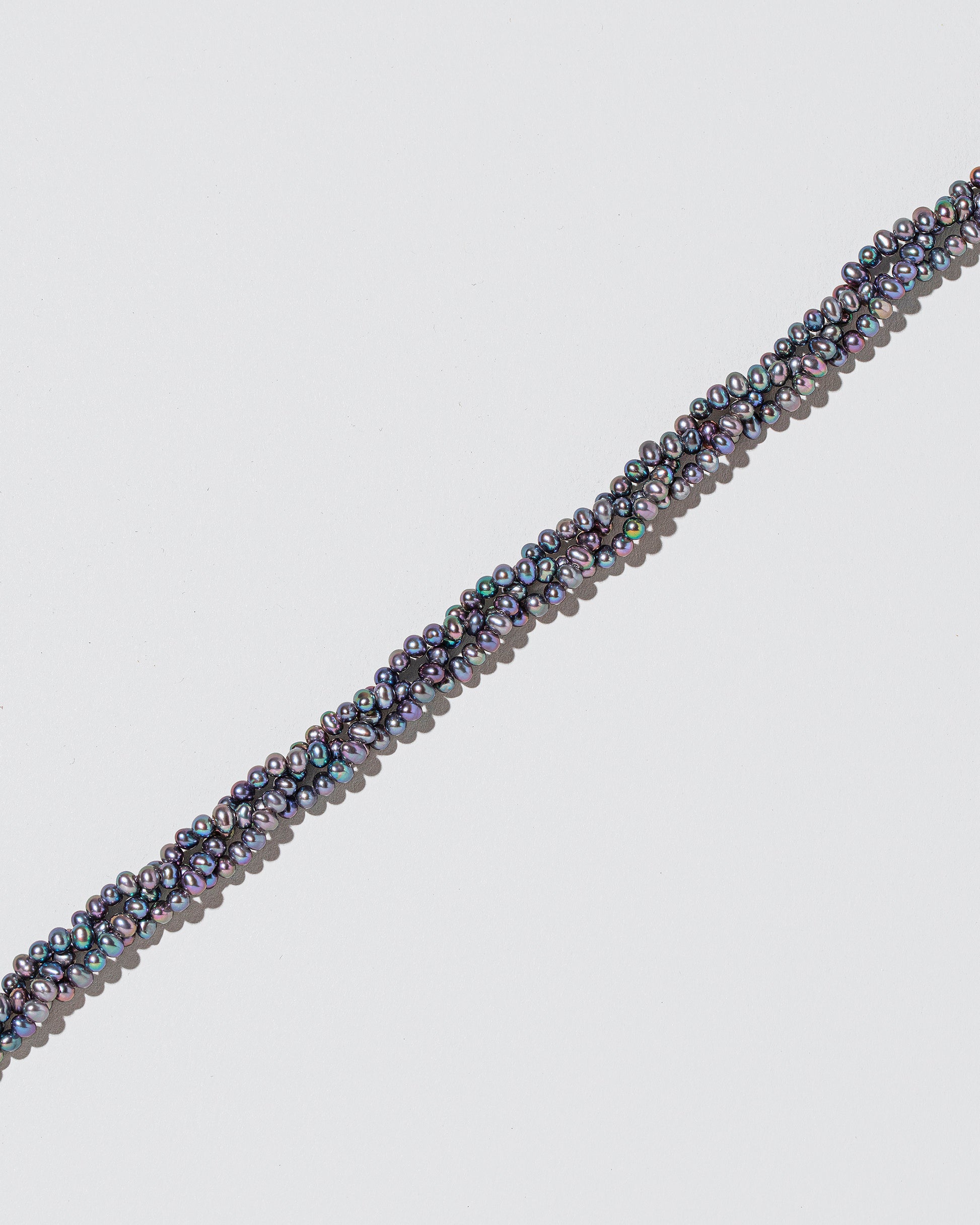 Closeup details of the Braided Seed Pearl Choker Necklace on light color background.