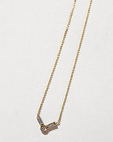 Closeup details of the Gold Baguette Bar Necklace on light color background.