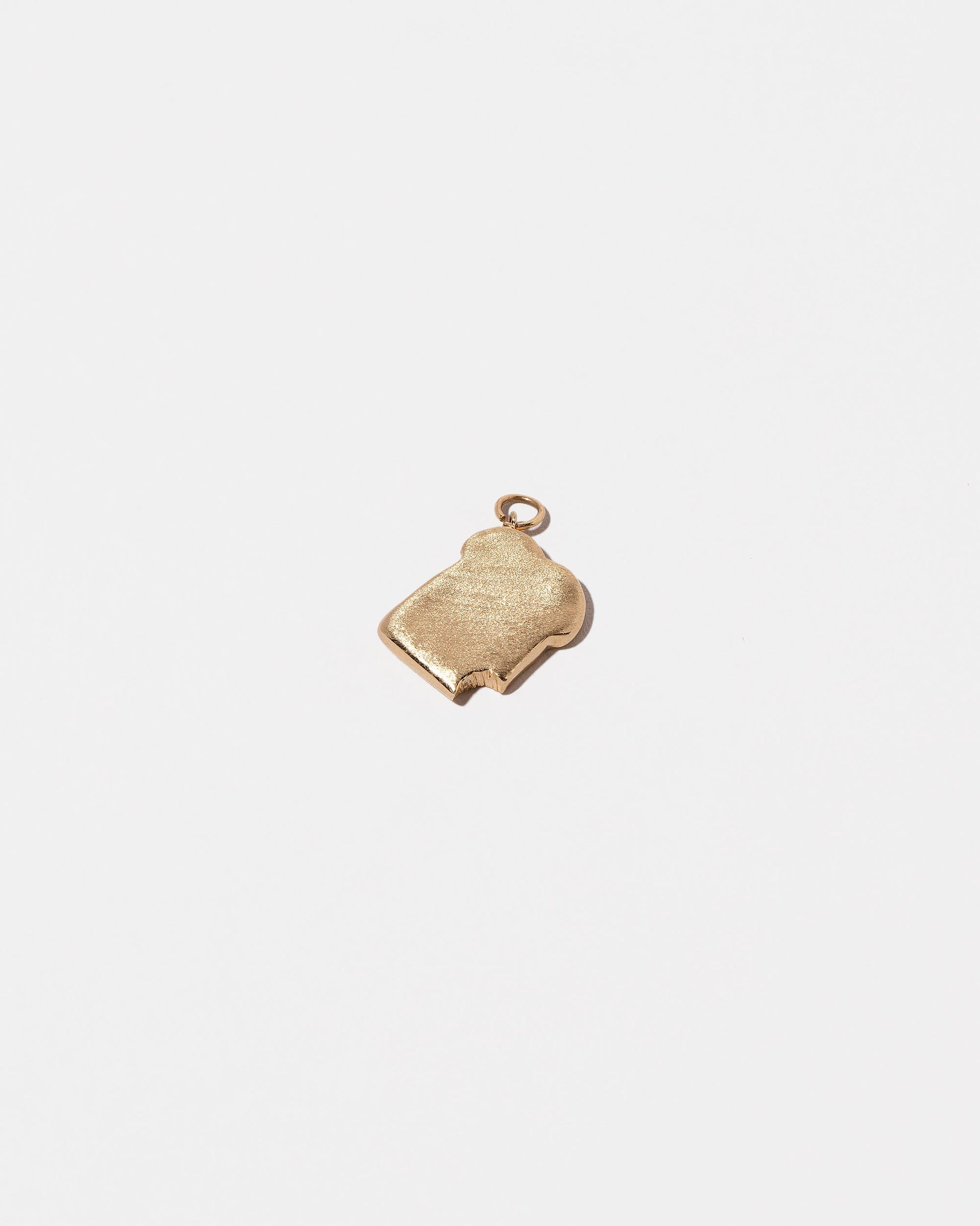 View from the back of the Bitten Toast Charm on light color background.