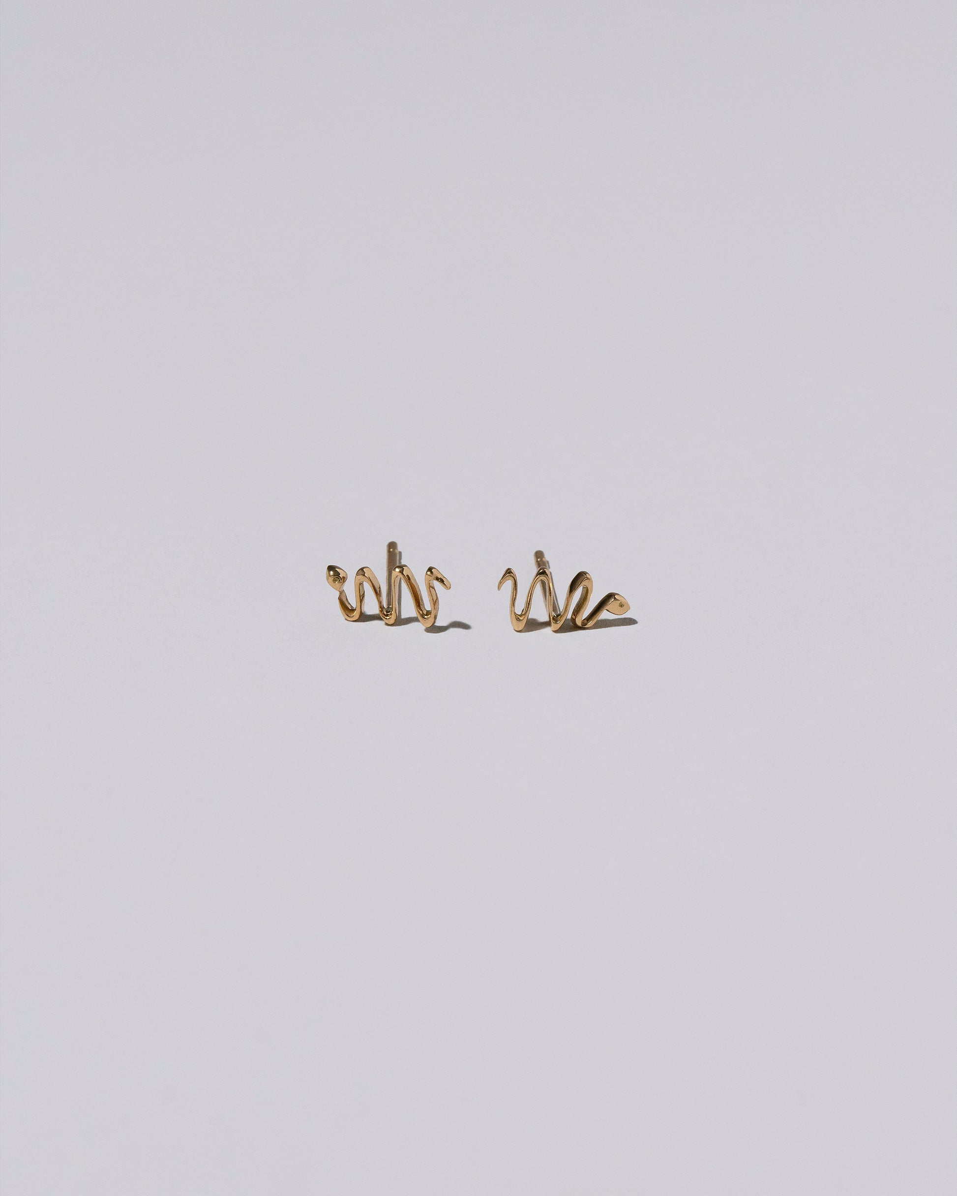 Right Snake Stud Earring Single and Left Snake Stud Earring Single on light color background.