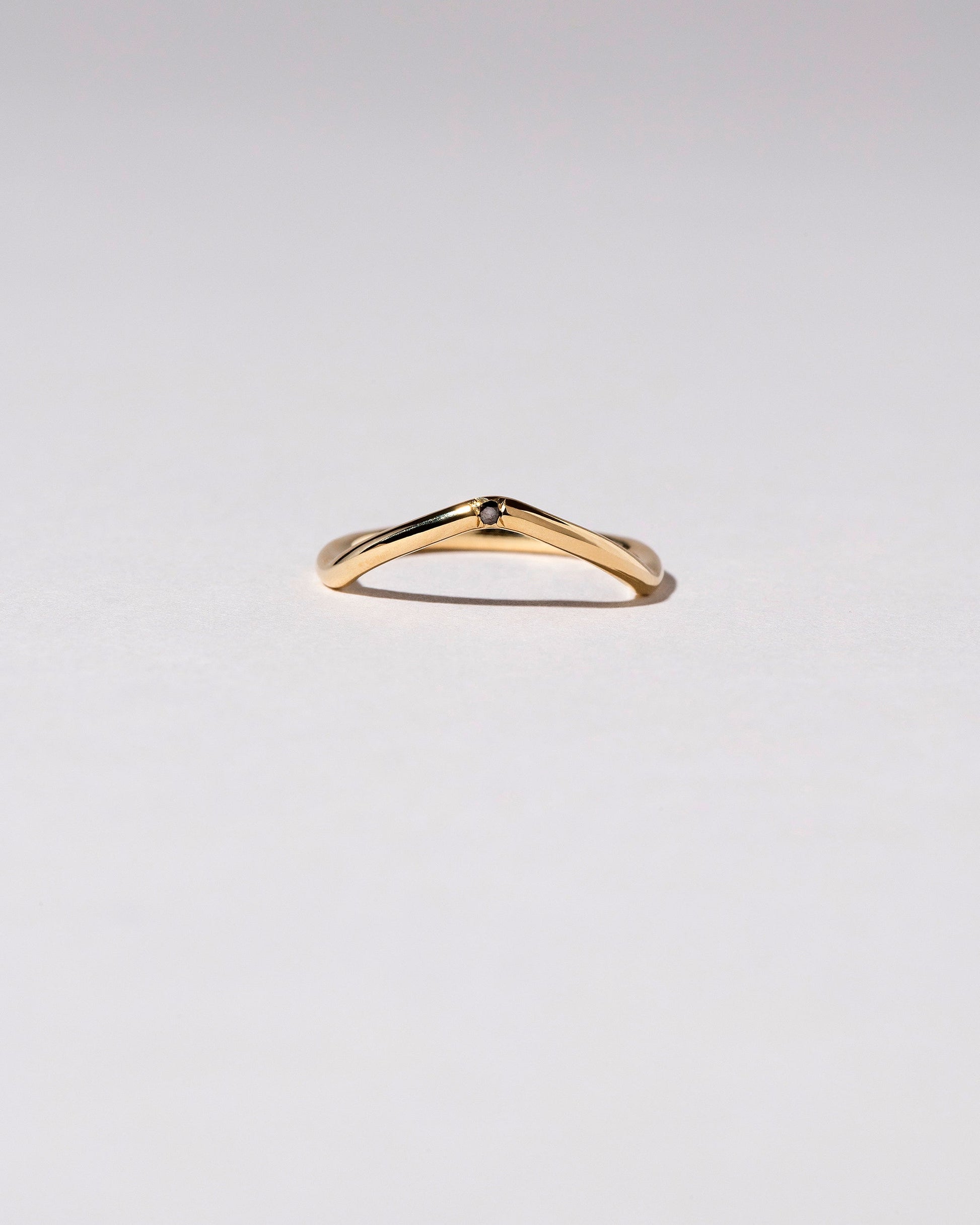 Gold Single Stone Black Diamond Low Peak Band on light color background.