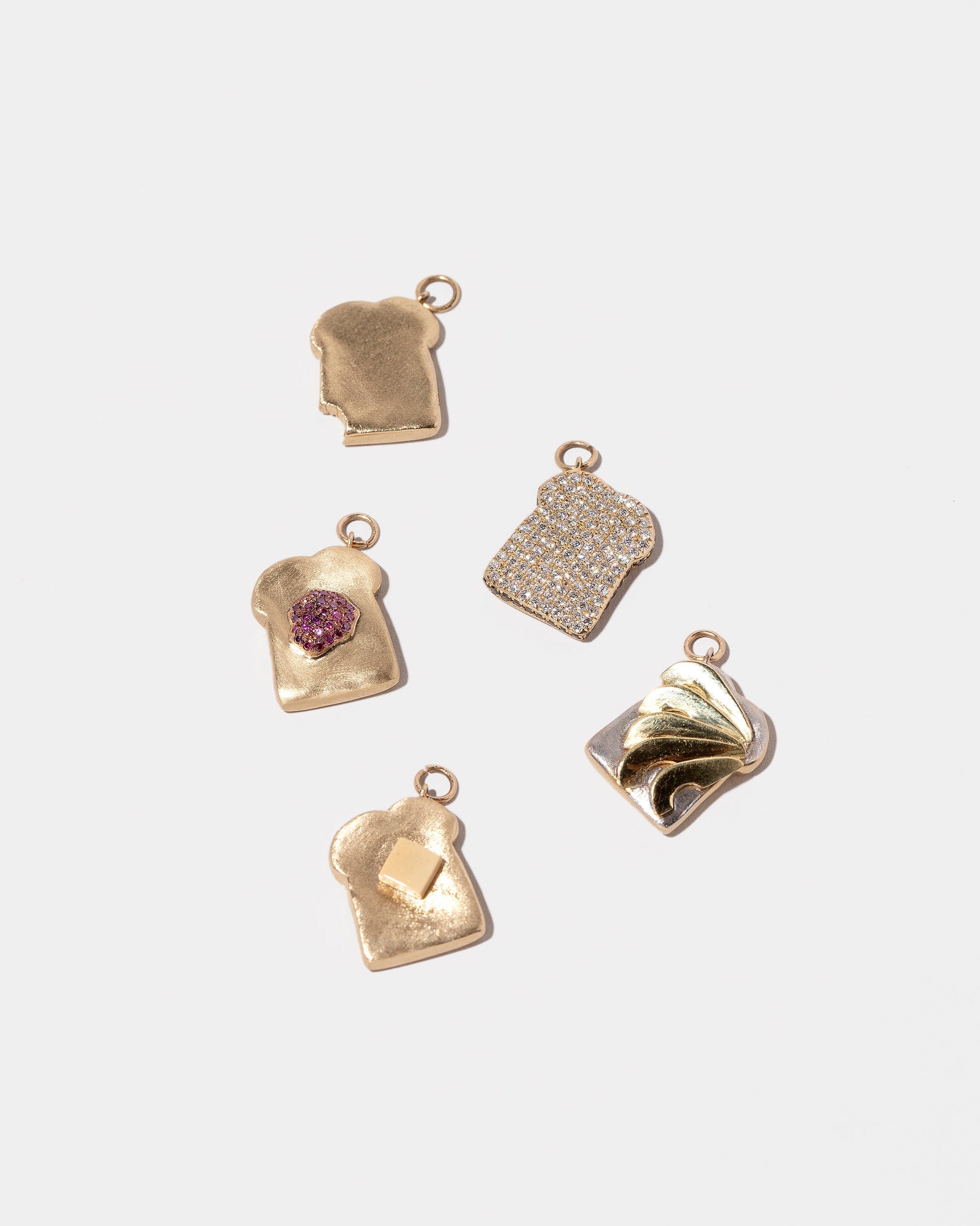 Closeup details of the Pavé Toast Charm, Jelly Toast Charm, Buttered Toast Charm, Bitten Toast Charm and Avocado Toast Charm on light color background.