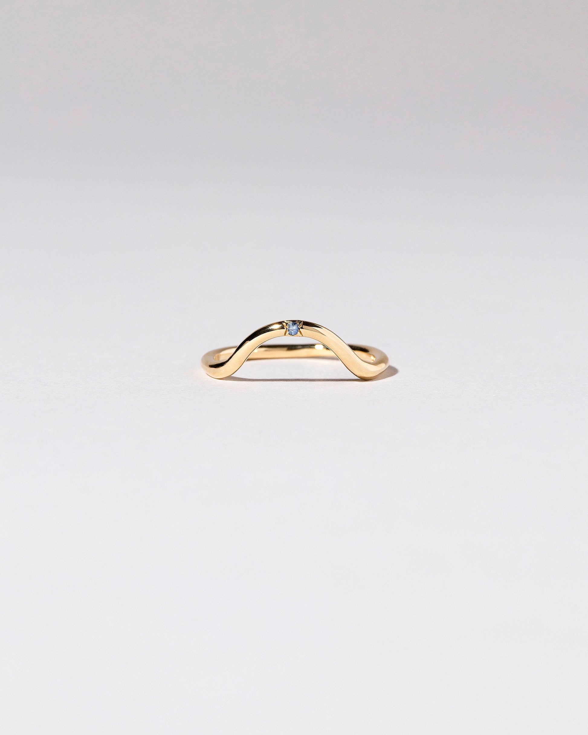 Gold Single Stone Blue Sapphire Curve Band on light color background.