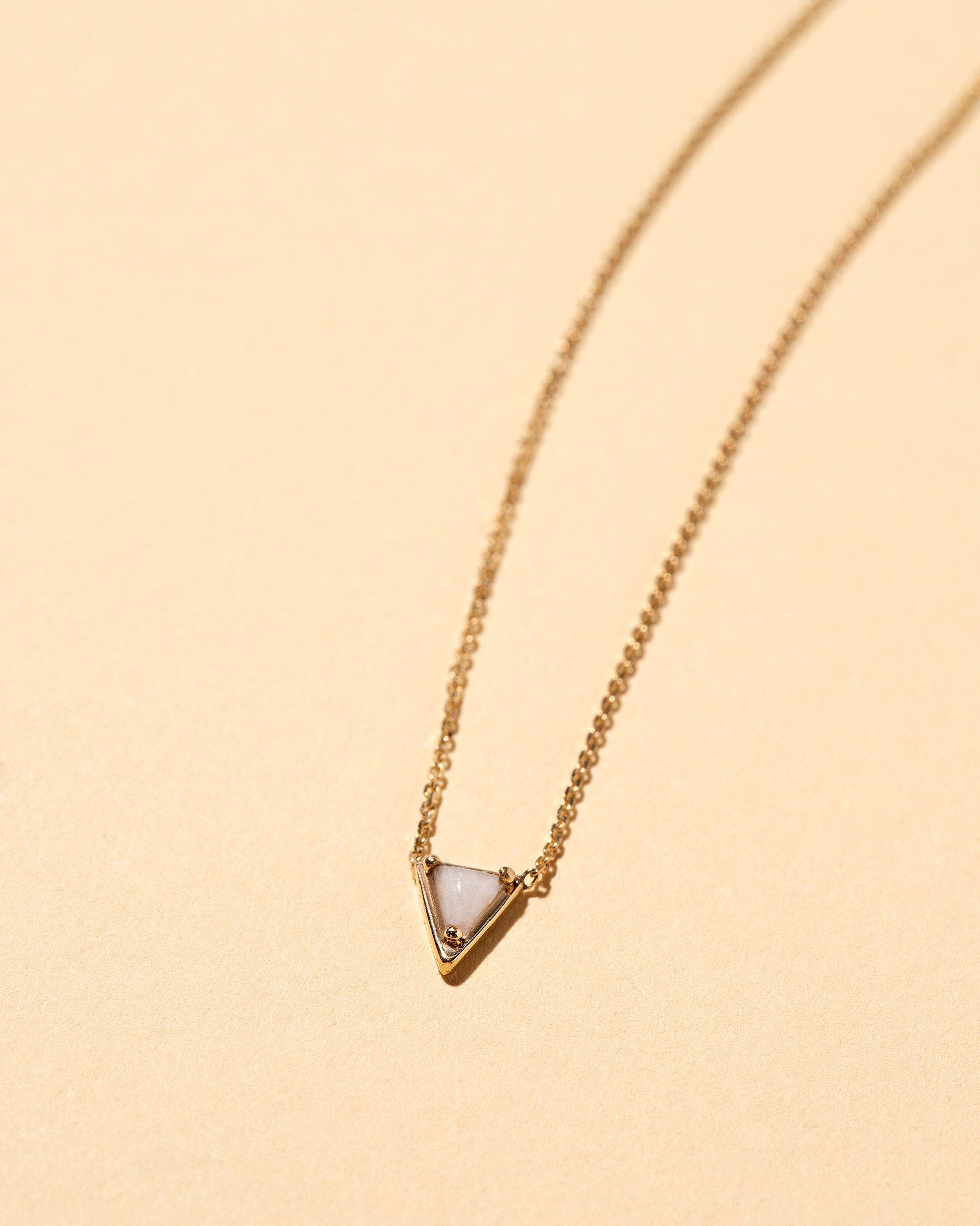 Closeup details of the Gold Snowdrift Agate Triangle Necklace on light color background.